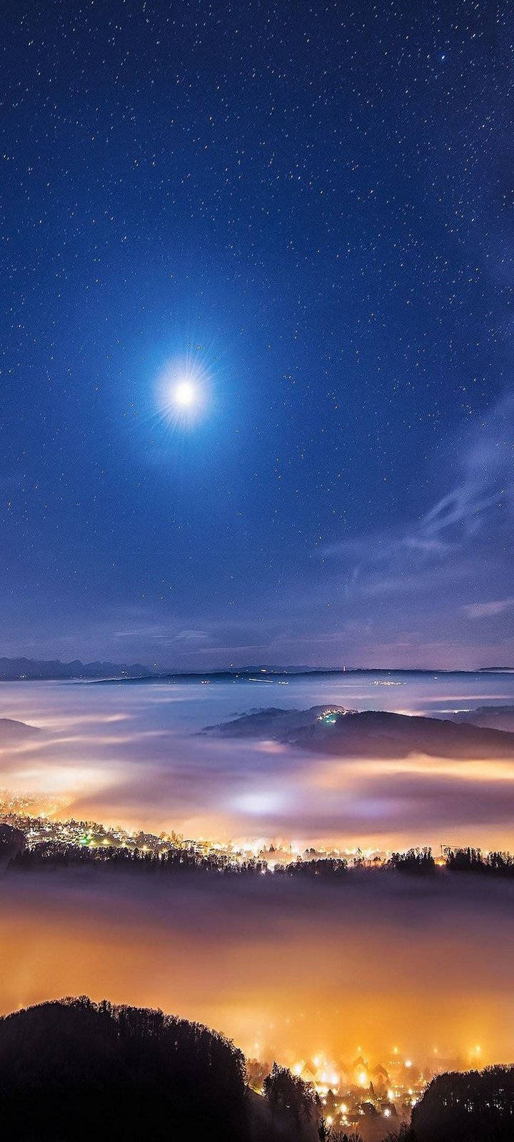夜空 桌布 壁紙 — 一輪明月照耀在發光的雲海之上，下方的小鎮沉浸在溫暖的燈光中。