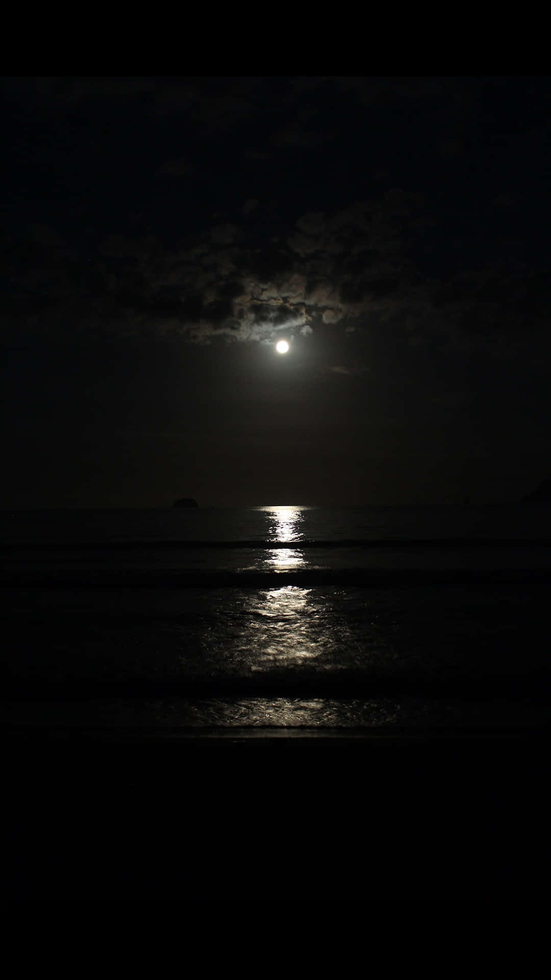 Dark Night 桌布 壁紙 — 一輪明月穿過烏雲，在夜晚平靜的海面上投射出一條閃爍的路徑。