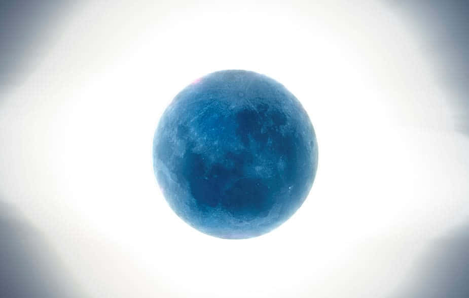 Perigee 桌布 壁紙 — 一輪鮮豔的藍色月亮在明亮的白色天空中發光，伴隨著柔和的漸變雲彩。