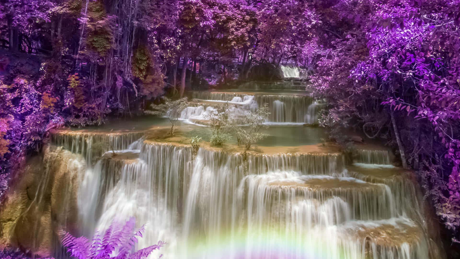Waterfalls 桌布 壁紙 — 一道層疊瀑布流過沐浴在超現實紫色光芒中的森林，底部有一道彩虹拱起。