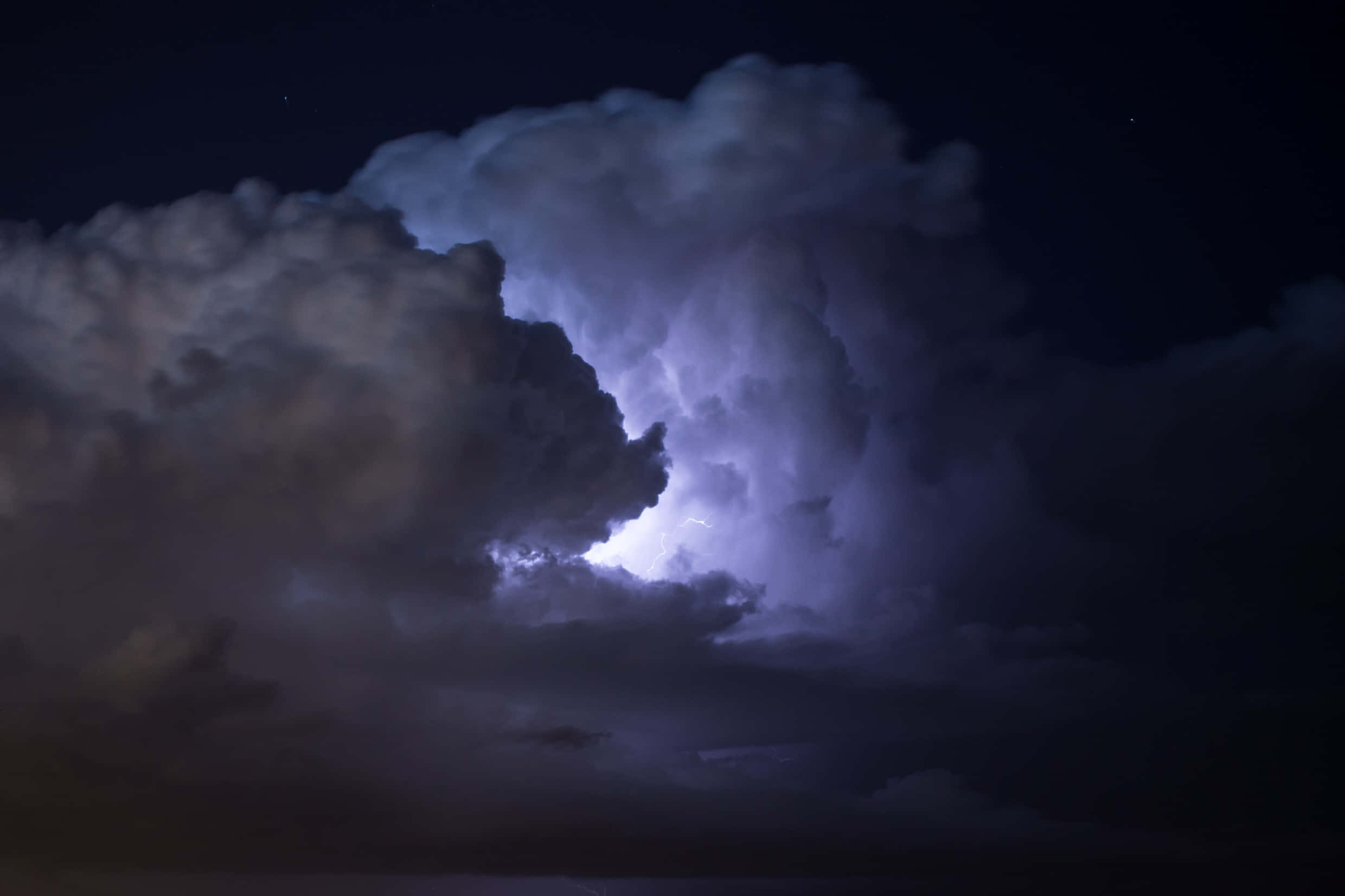 Dark Storm 桌布 壁紙 — 一道強勁的閃電照亮了黑暗夜空中的巨大風暴雲，並可見星星。