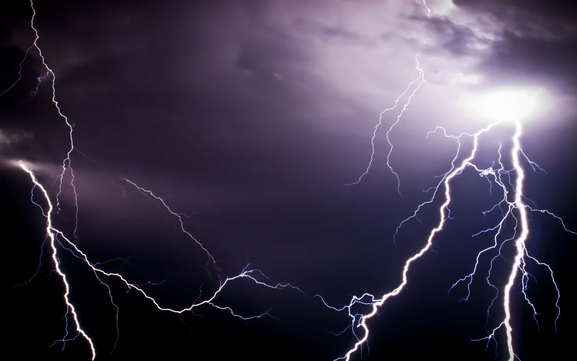 強大的閃電以紫色和白色閃光照亮了黑暗的暴風雨天空。