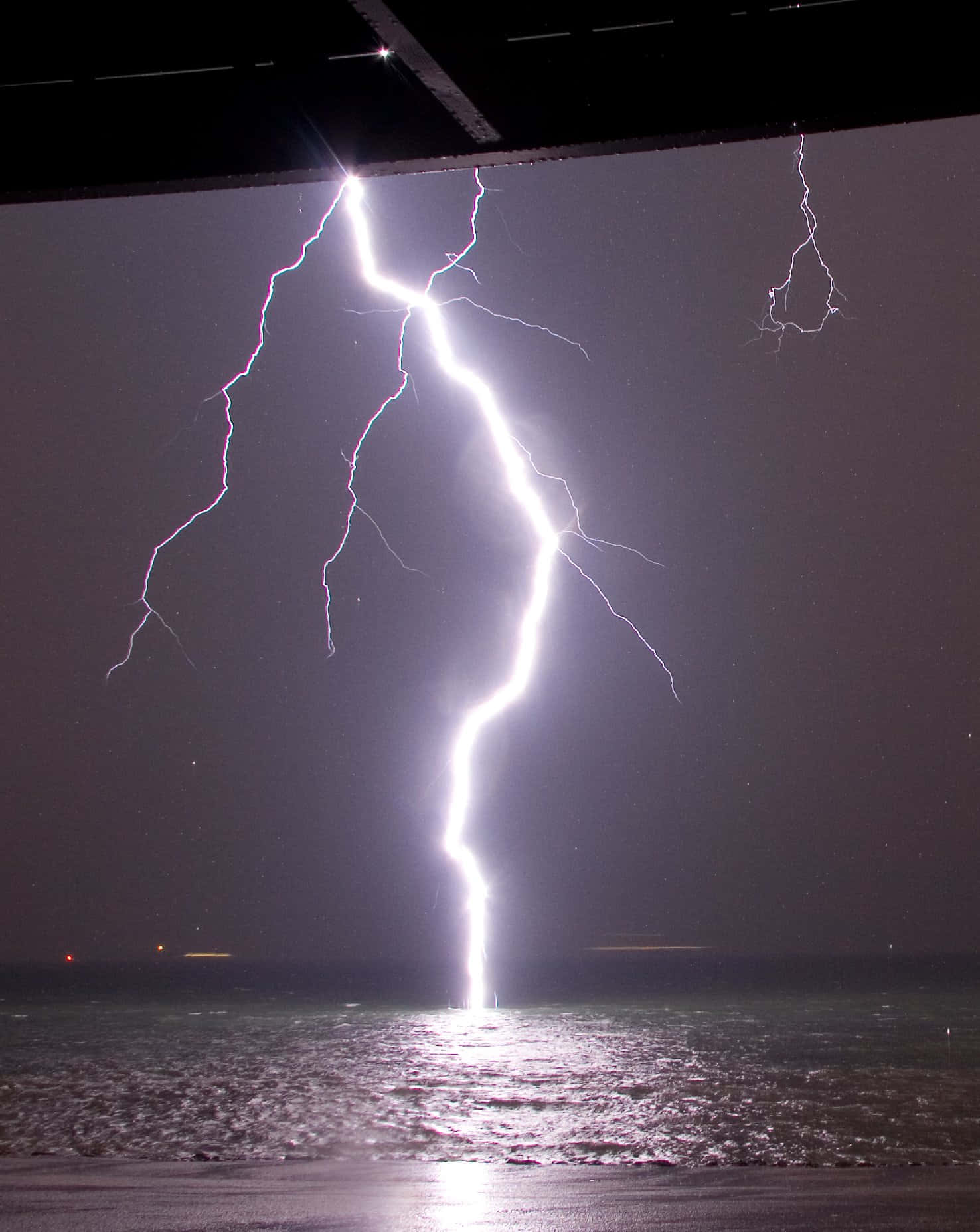 閃電在夜間擊中海洋，用明亮的白光照亮水面。