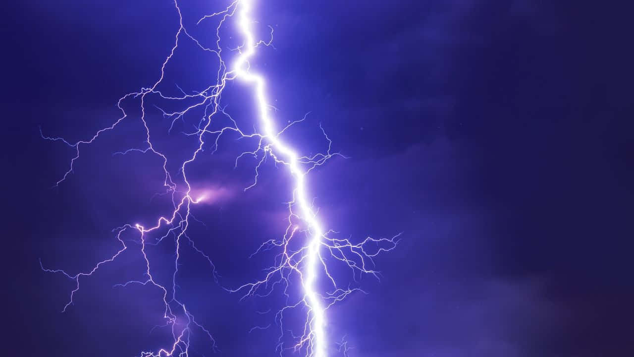 Thunderstorm 桌布 壁紙 — 一道強大的閃電在深紫色的暴風雨天空中分叉，照亮了鋸齒狀的電能分支。