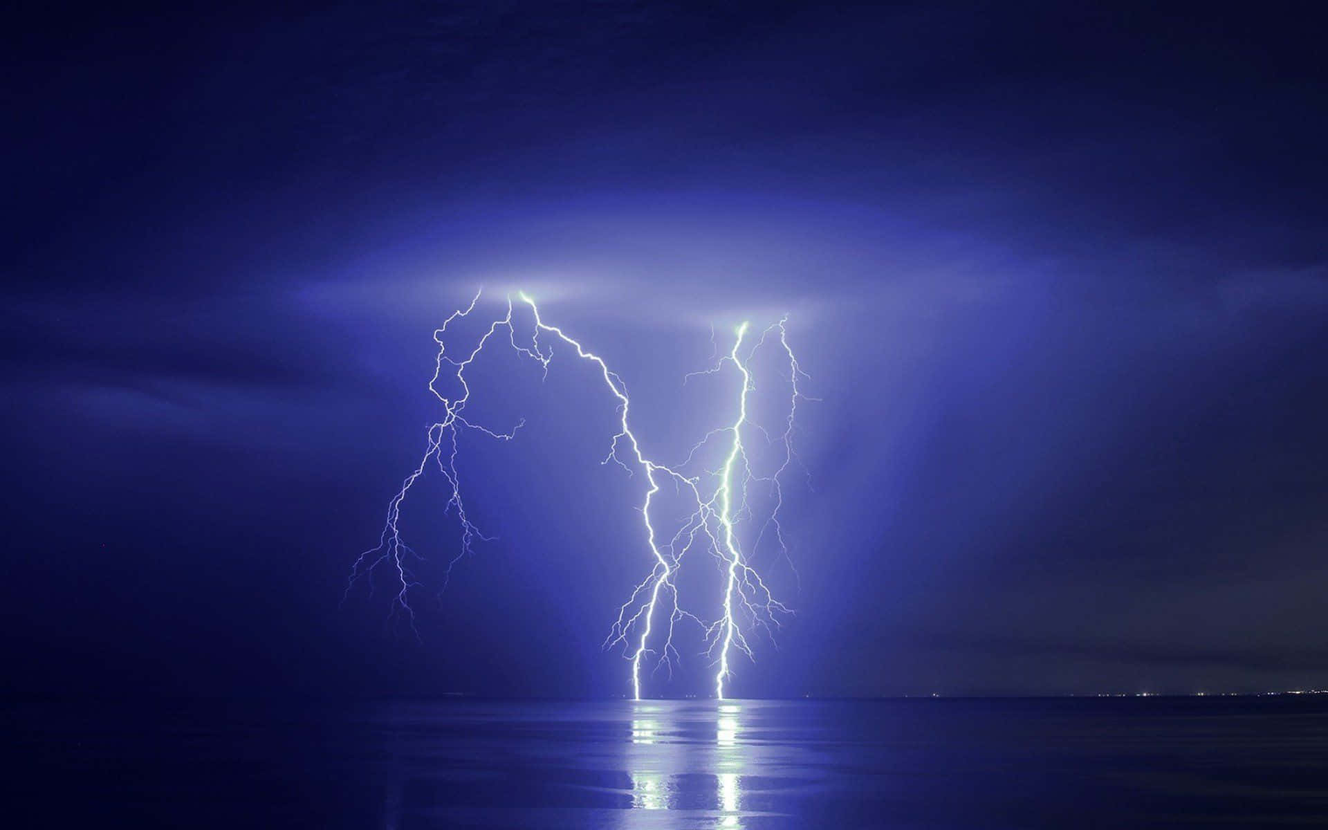 thunder 桌布 壁紙 — 一道強大的閃電照亮了夜晚平靜反射的海面上方黑暗暴風雨的天空。