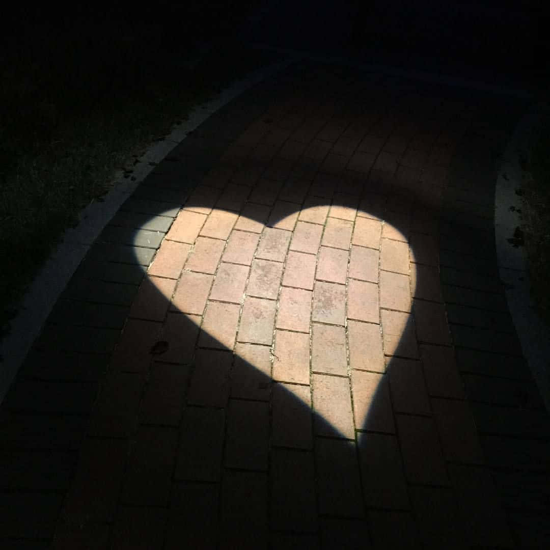 Heart Shape 桌布 壁紙 — 一道心形光束照亮了夜晚的磚砌小路，兩側投下深深的陰影。