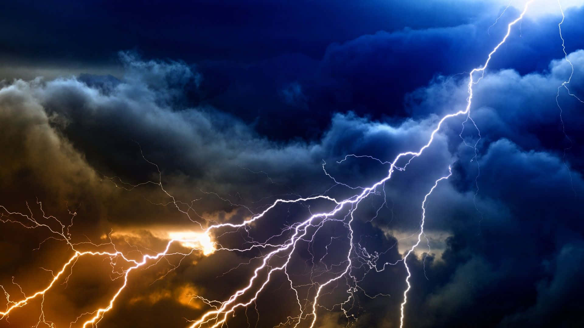 Thunderstorm 桌布 壁紙 — 一道戲劇性的天空被鮮明的閃電劈開，照亮了黑暗的暴風雲，帶有火橙色和電光藍的色調。