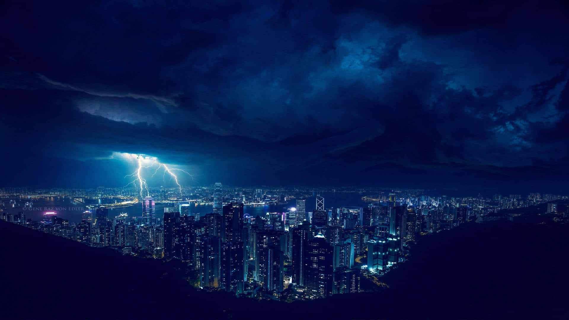 Cityscape 桌布 壁紙 — 一道戲劇性的閃電照亮了夜晚廣闊的城市景觀，閃爍的摩天大樓和頭頂上黑暗的暴風雲。
