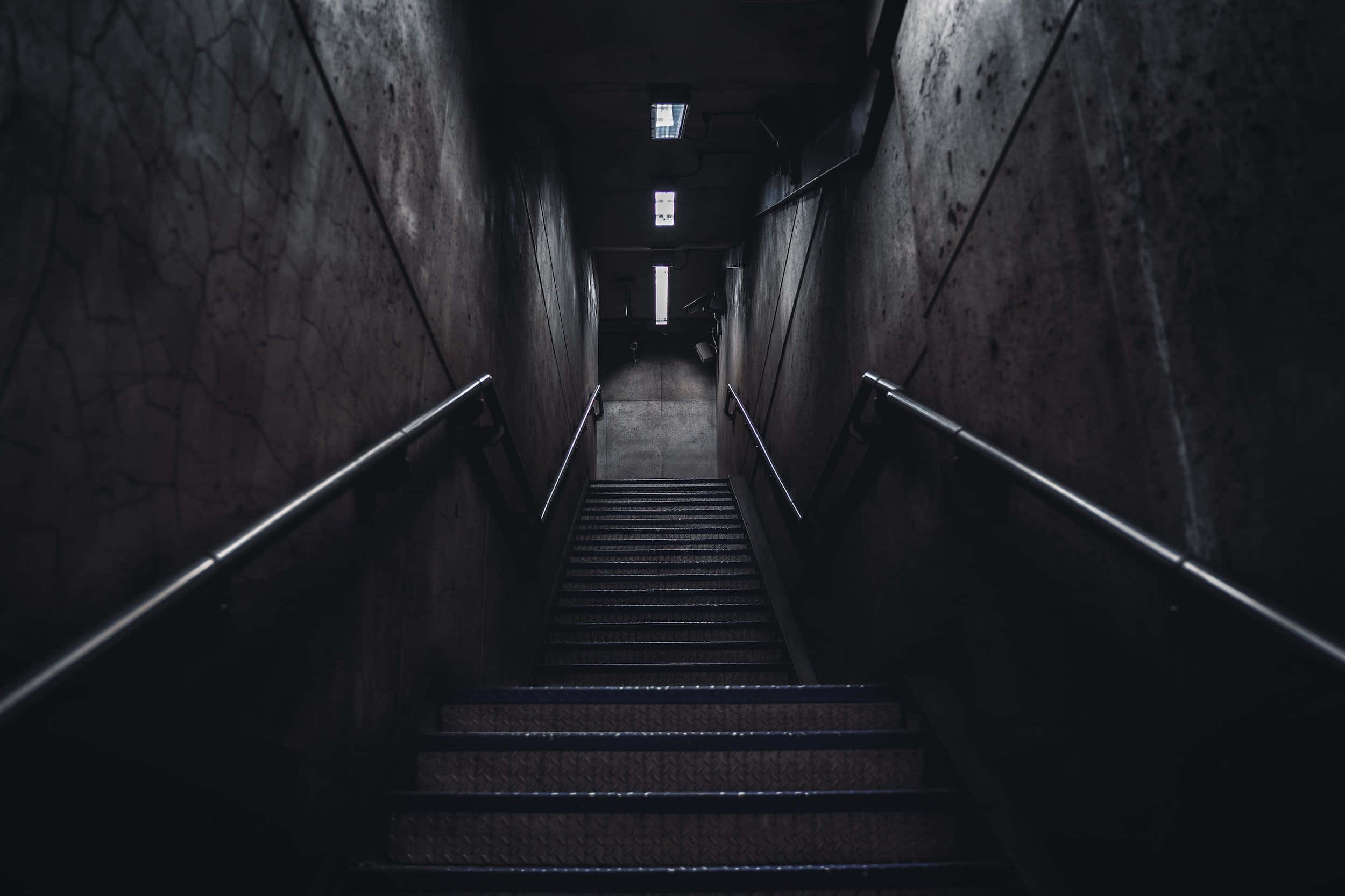 Dark Underground 桌布 壁紙 — 一道昏暗的混凝土樓梯向上延伸，進入陰影黑暗之中，微弱的光線從上方滲入。