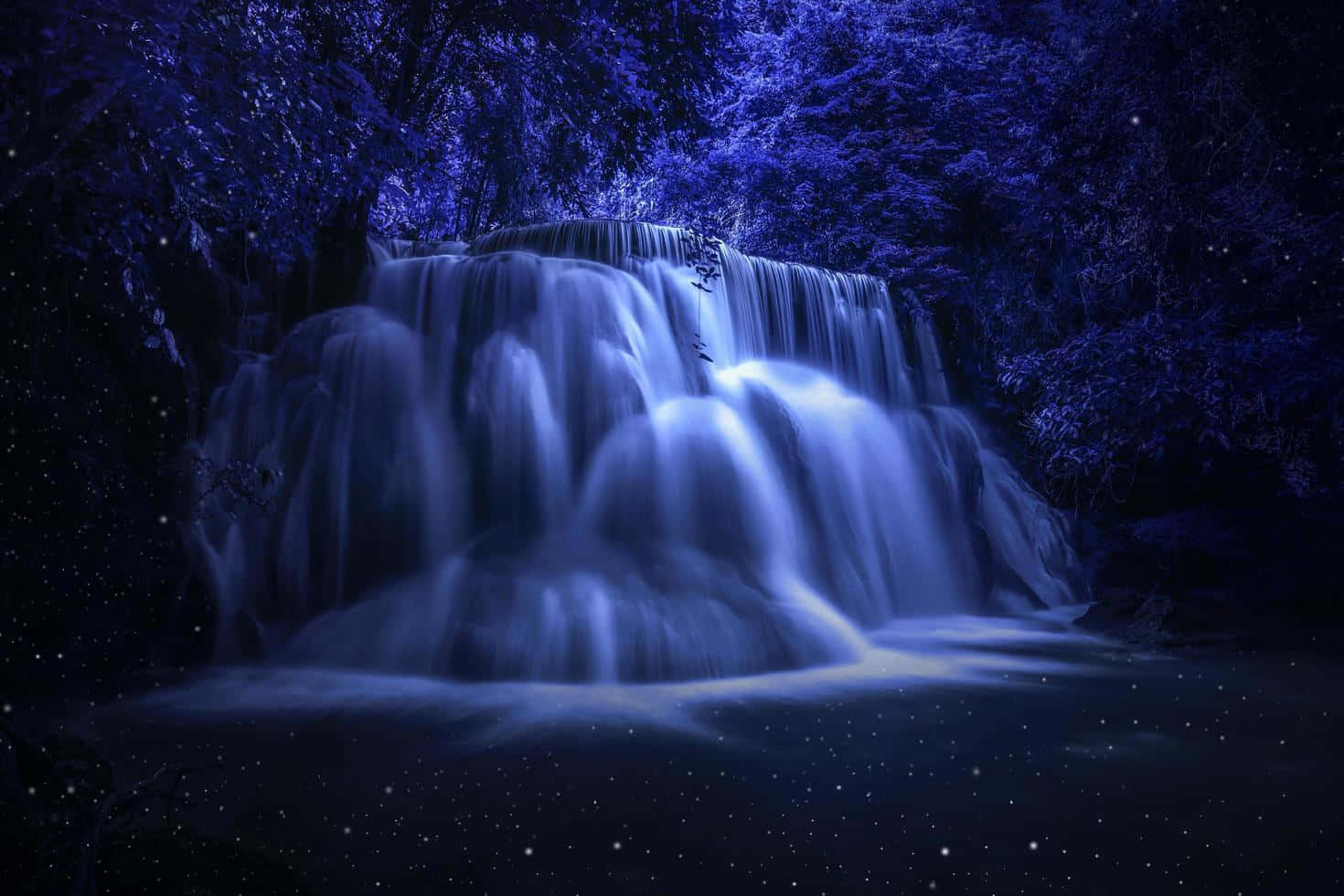 Nature Scenery 桌布 壁紙 — 一道發光的藍色瀑布穿過星光燦爛的夜晚森林，伴隨著發光的薄霧和黑暗的樹木。