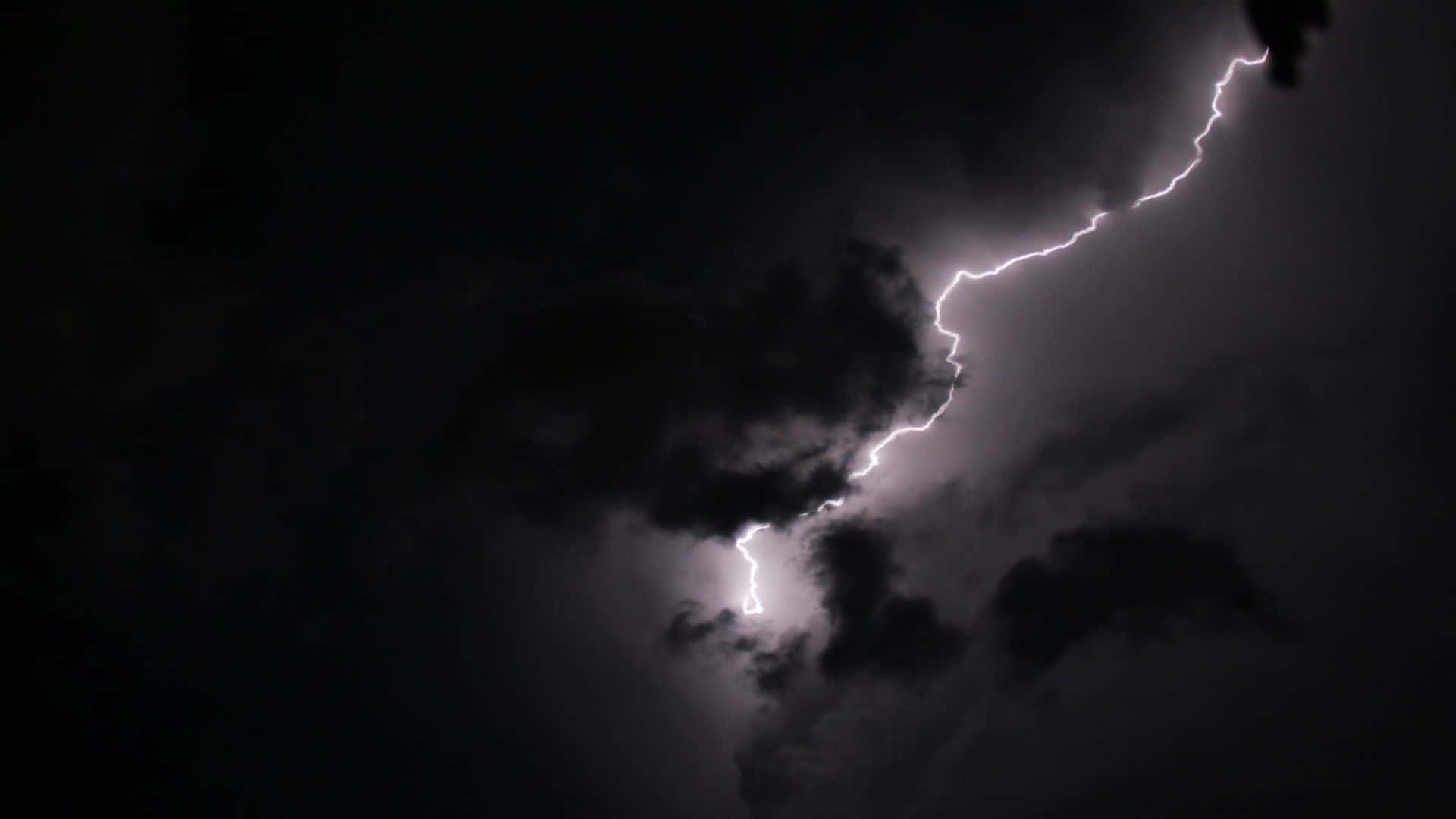 Dark Night 桌布 壁紙 — 一道鋸齒狀閃電劃破黑暗的暴風雨天空，照亮了旋轉的雲層，構成戲劇性的夜間景象。