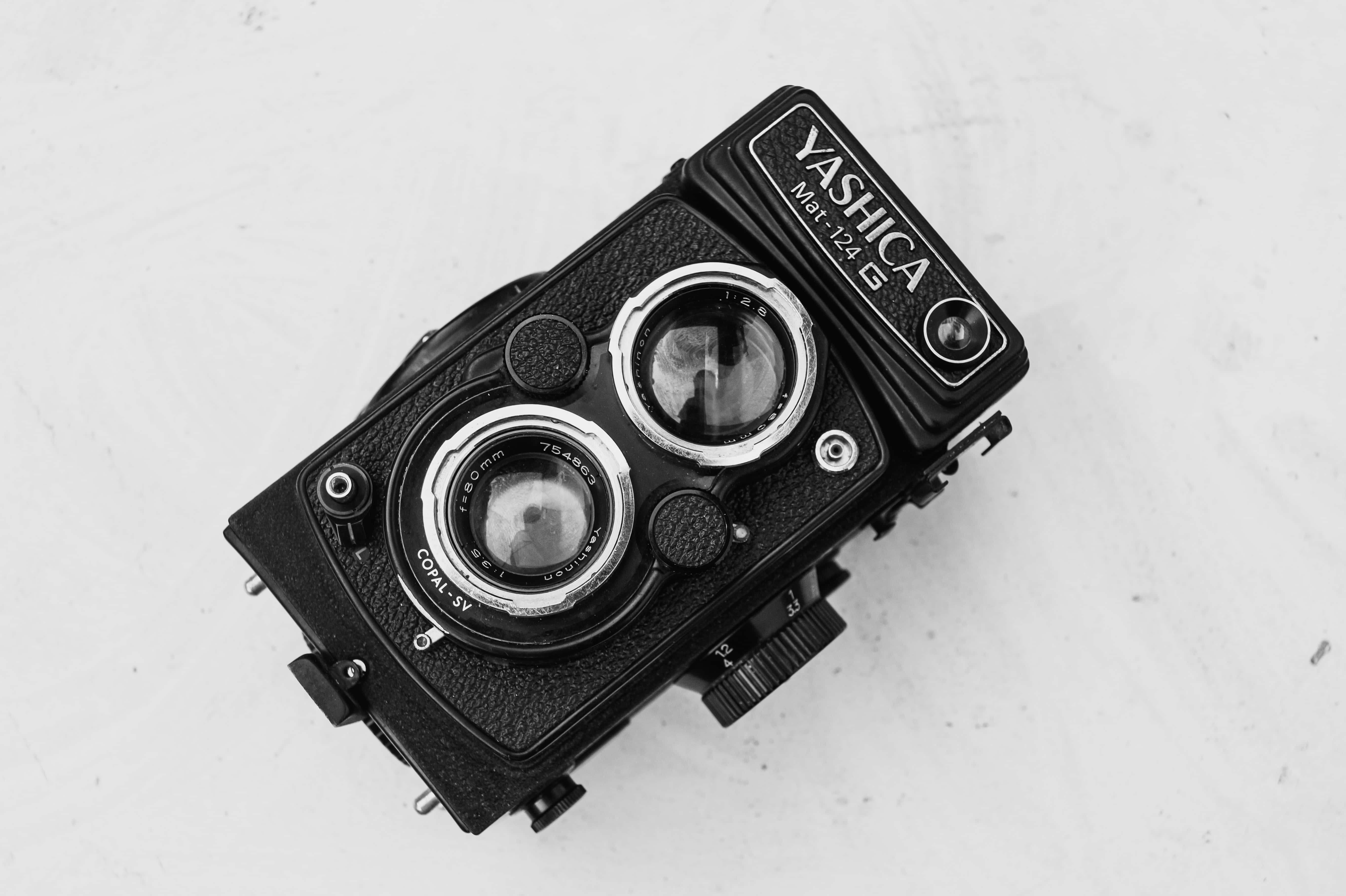 黑白美學 桌布 壁紙 — 一部復古Yashica Mat 124G雙鏡反光相機放置在白色表面上，以單色呈現。