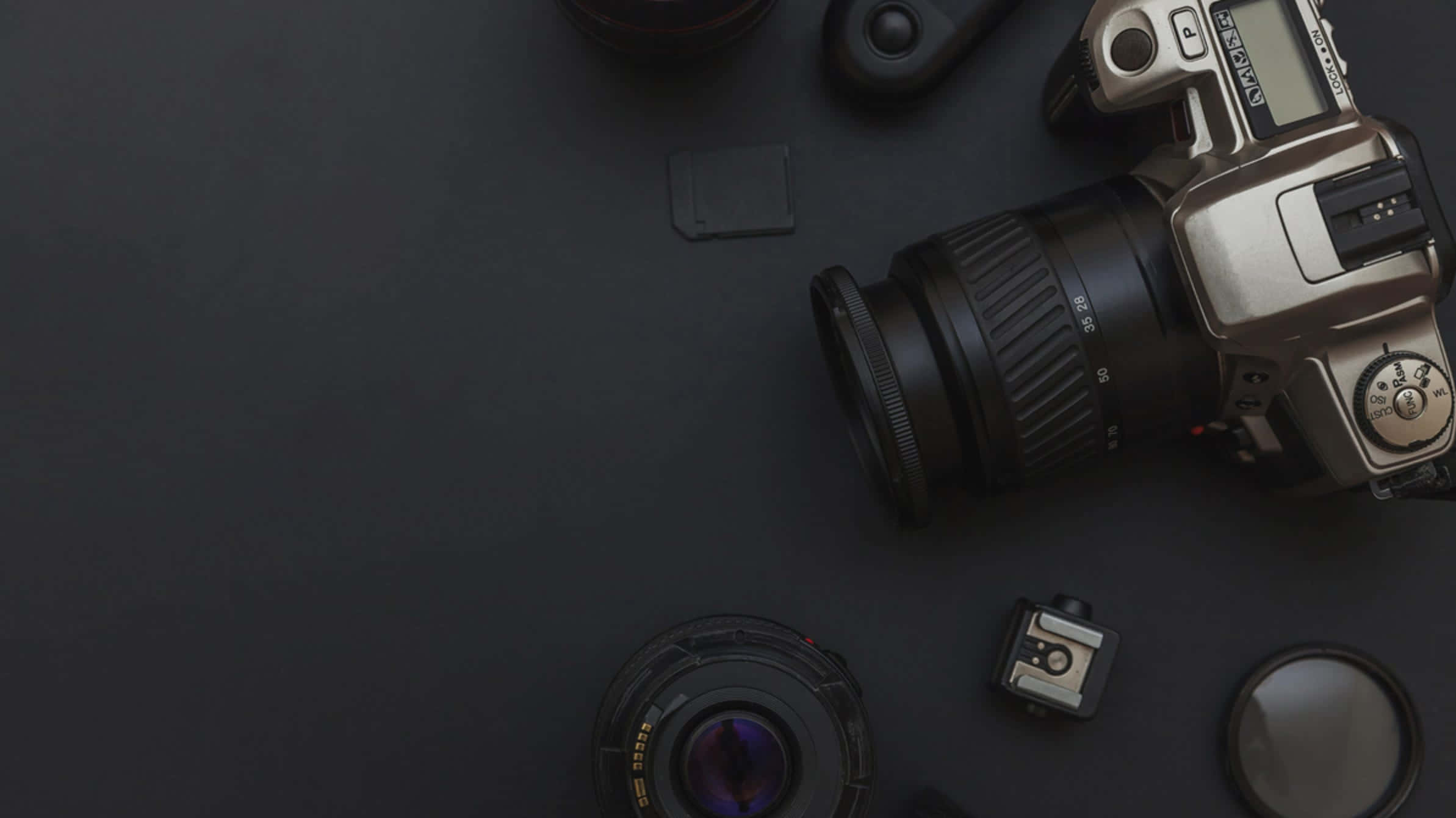 Dslr Camera 桌布 壁紙 — 一部復古相機和鏡頭排列在深色啞光表面上，形成極簡的平鋪構圖。