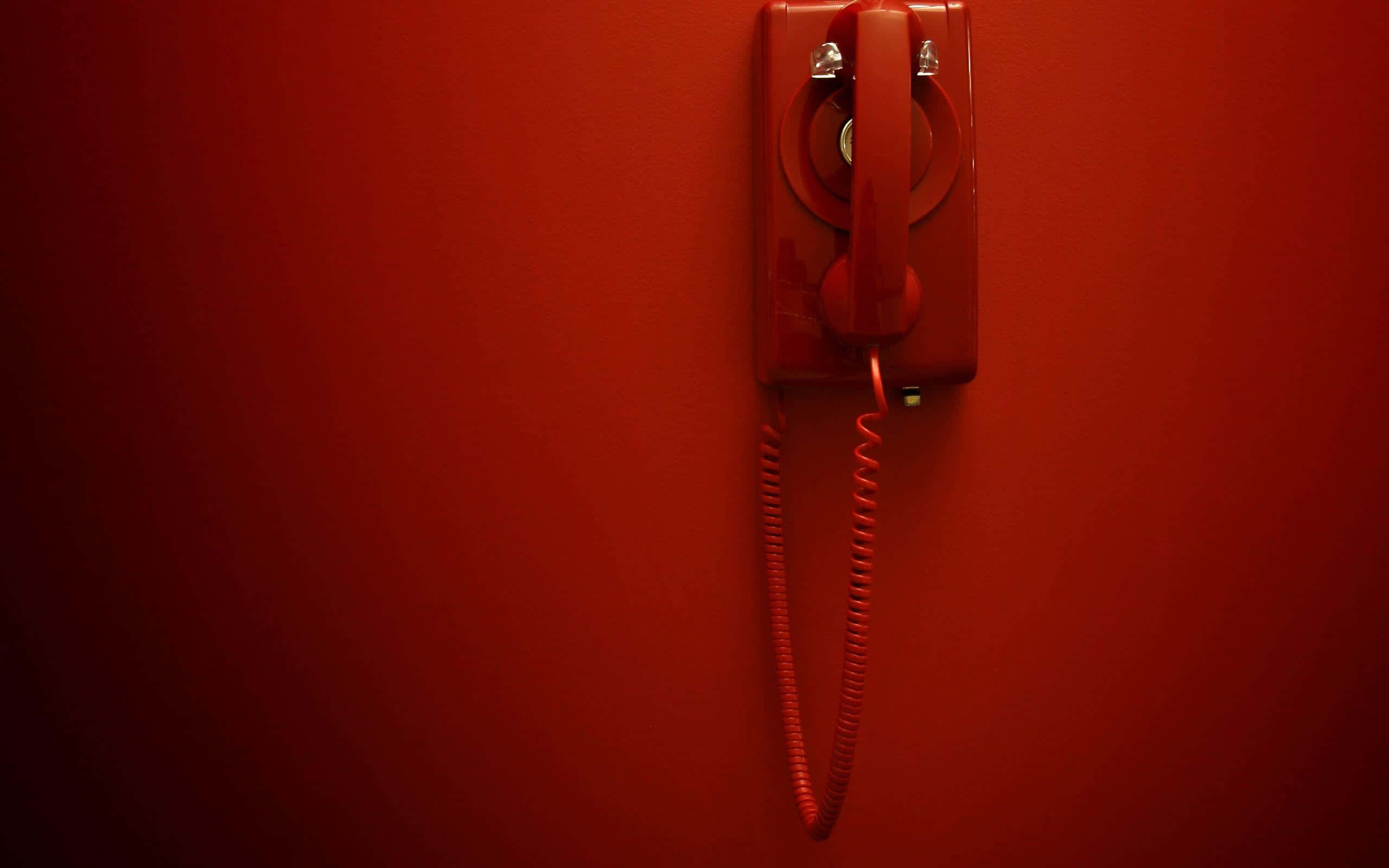 Phone Call 桌布 壁紙 — 一部復古紅色轉盤電話安裝在相配的紅色牆上，帶有戲劇性的燈光。