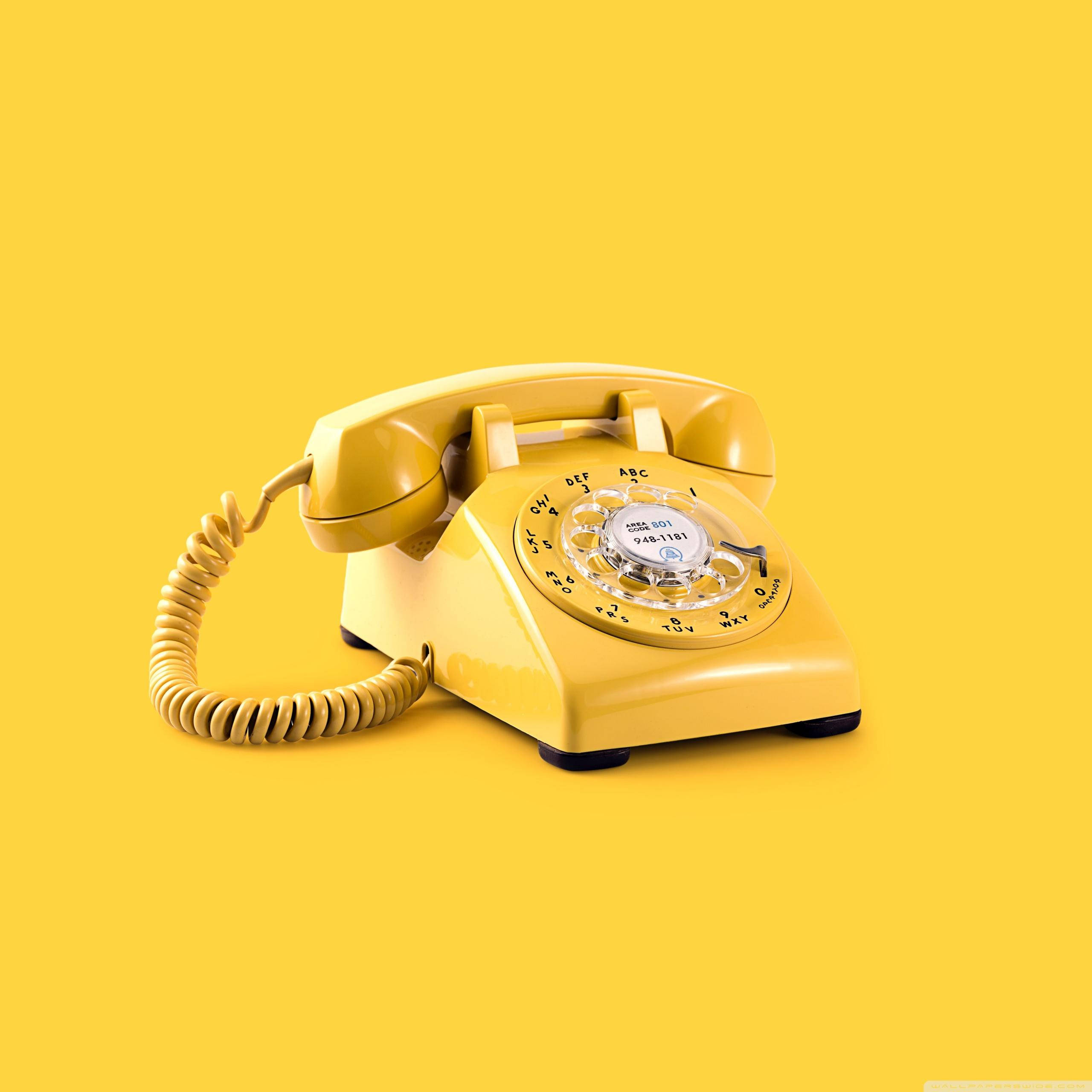 Vintage Aesthetic 桌布 壁紙 — 一部復古黃色旋轉撥號電話居中放置在純黃色背景上，帶有柔和陰影。