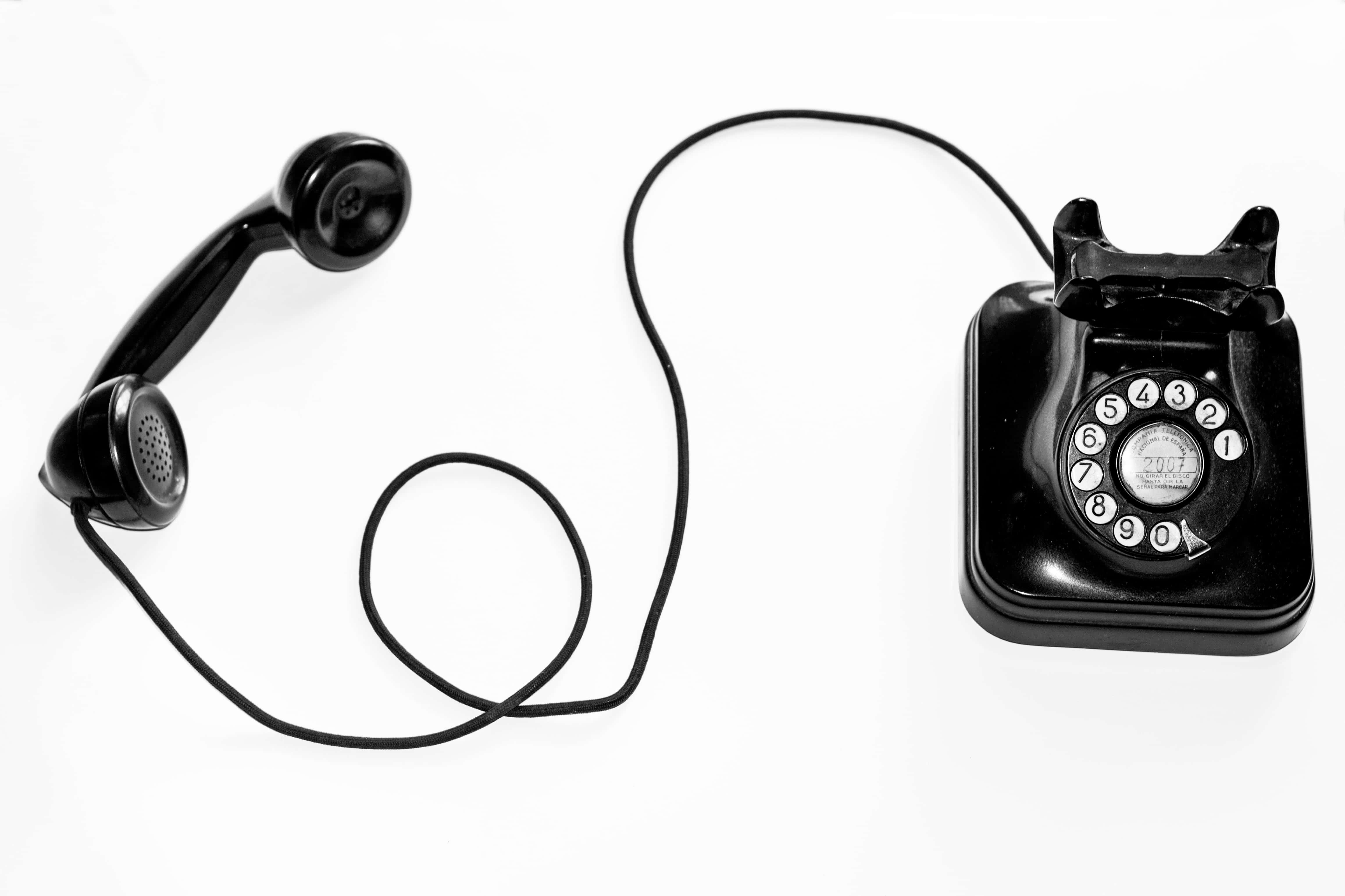 Phone Call 桌布 壁紙 — 一部復古黑色旋轉撥號電話，聽筒擱在潔白背景上。