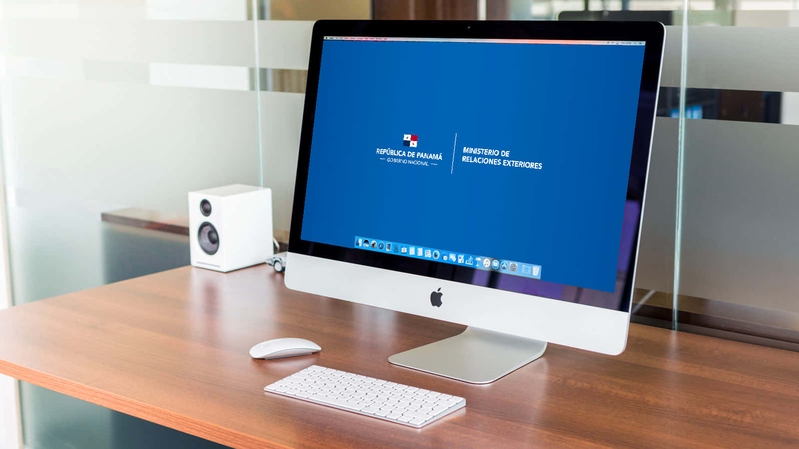 Multimedia 桌布 壁紙 — 一部時尚的 iMac 放在木桌上，顯示巴拿馬外交部首頁，旁邊有白色鍵盤和揚聲器。