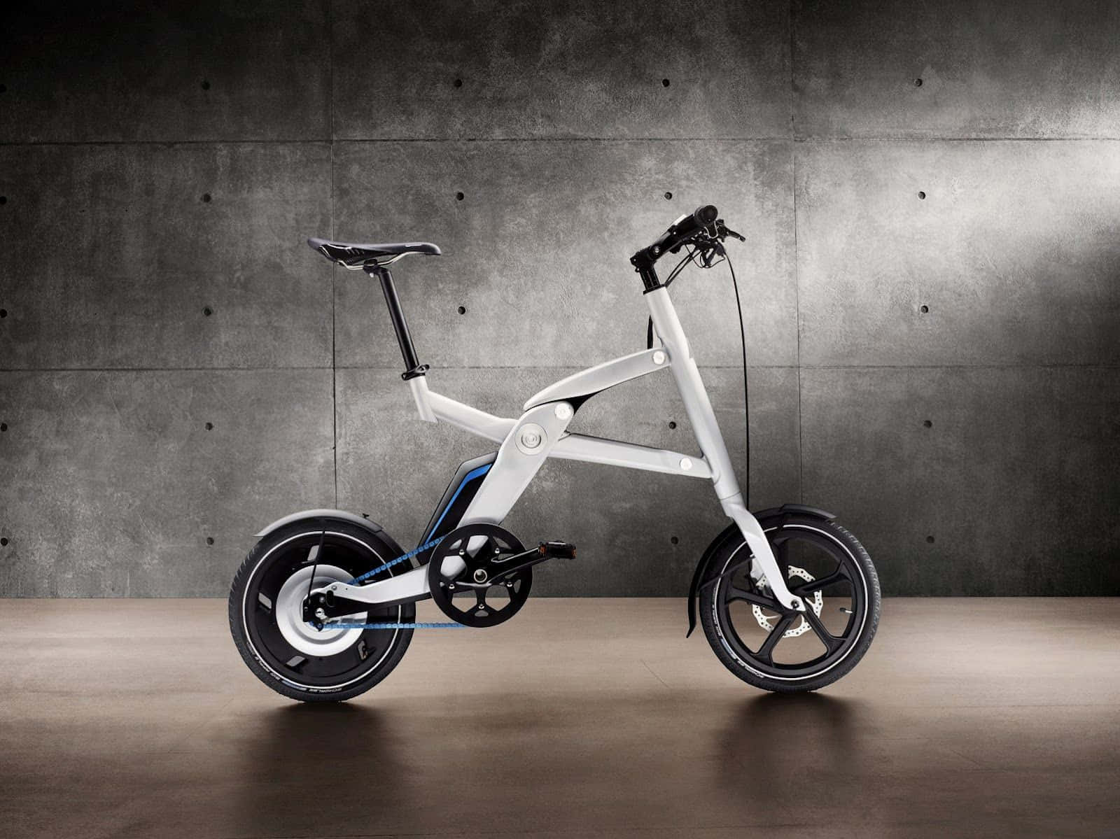Electric Bike 桌布 壁紙 — 一部時尚的白色折疊電動自行車，帶有黑色點綴，在極簡主義工作室中，矗立在帶紋理的灰色混凝土牆前。