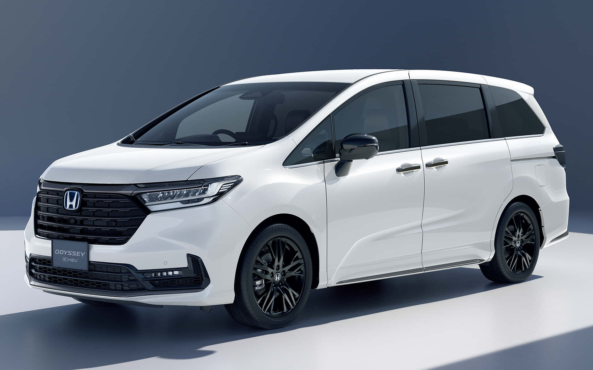 Honda Odyssey 桌布 壁紙 — 一部時尚的白色本田Odyssey小型客貨車，帶有黑色飾邊和現代化頭燈，在簡約的攝影棚環境中展示。