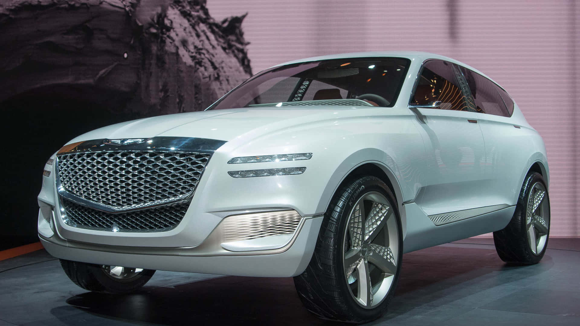 Genesis Gv80 桌布 壁紙 — 一部時尚的白色概念SUV，配備鍍鉻格柵和未來感車頭燈，在明亮的燈光下於舞台上展示。