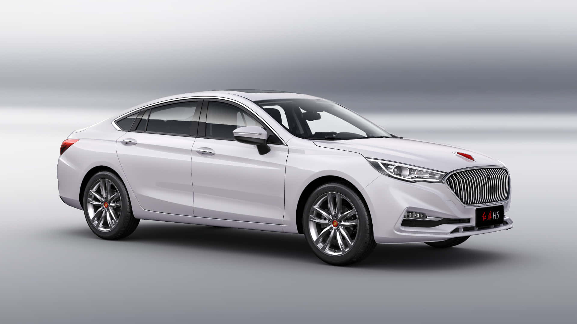 Hongqi 桌布 壁紙 — 一部時尚的白色豪華轎車，帶有鍍鉻飾邊和紅色徽章，在極簡灰色漸變工作室背景前蓄勢待發。