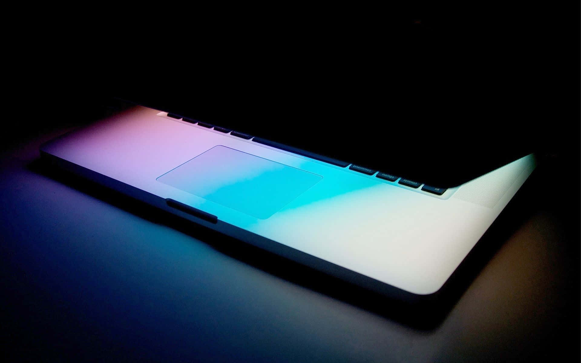 Best Laptop 桌布 壁紙 — 一部時尚的筆記型電腦在黑暗背景下散發出鮮豔的藍色和粉紅色光芒。
