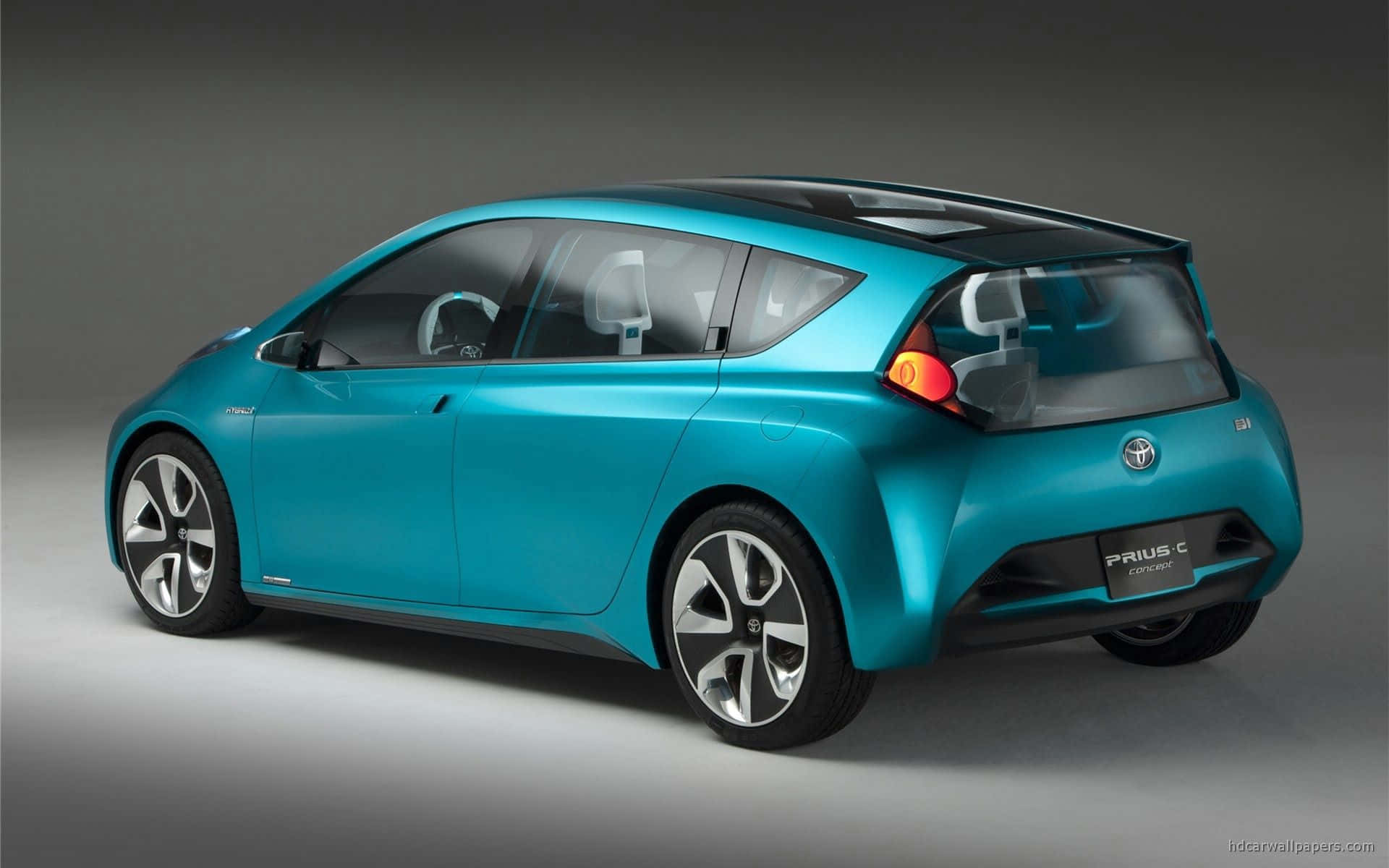 Hybrid Car 桌布 壁紙 — 一部時尚的藍綠色豐田Prius C概念車，在工作室燈光下以簡約灰色背景展示。