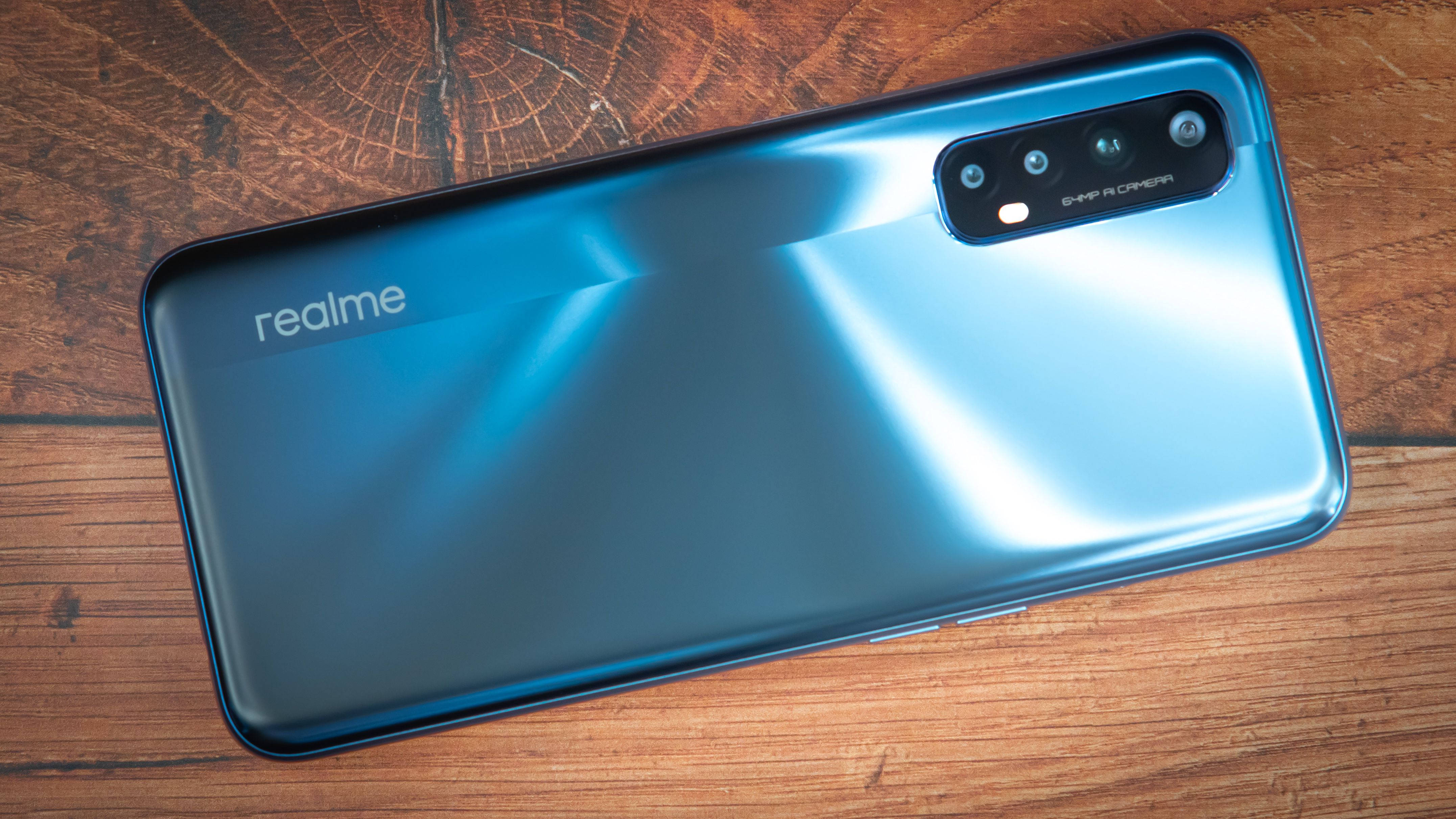 Realme 7 Pro 壁紙 — 一部時尚的藍色 realme 智能手機，配備四攝模組，放置在質樸的木質表面上。