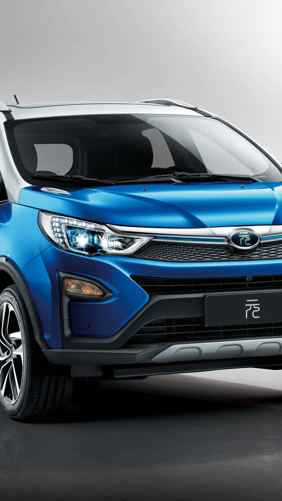 Byd 桌布 壁紙 — 一部時尚的藍色電動SUV，帶有鍍鉻飾邊和銳利頭燈，在簡約的攝影棚環境中展示。