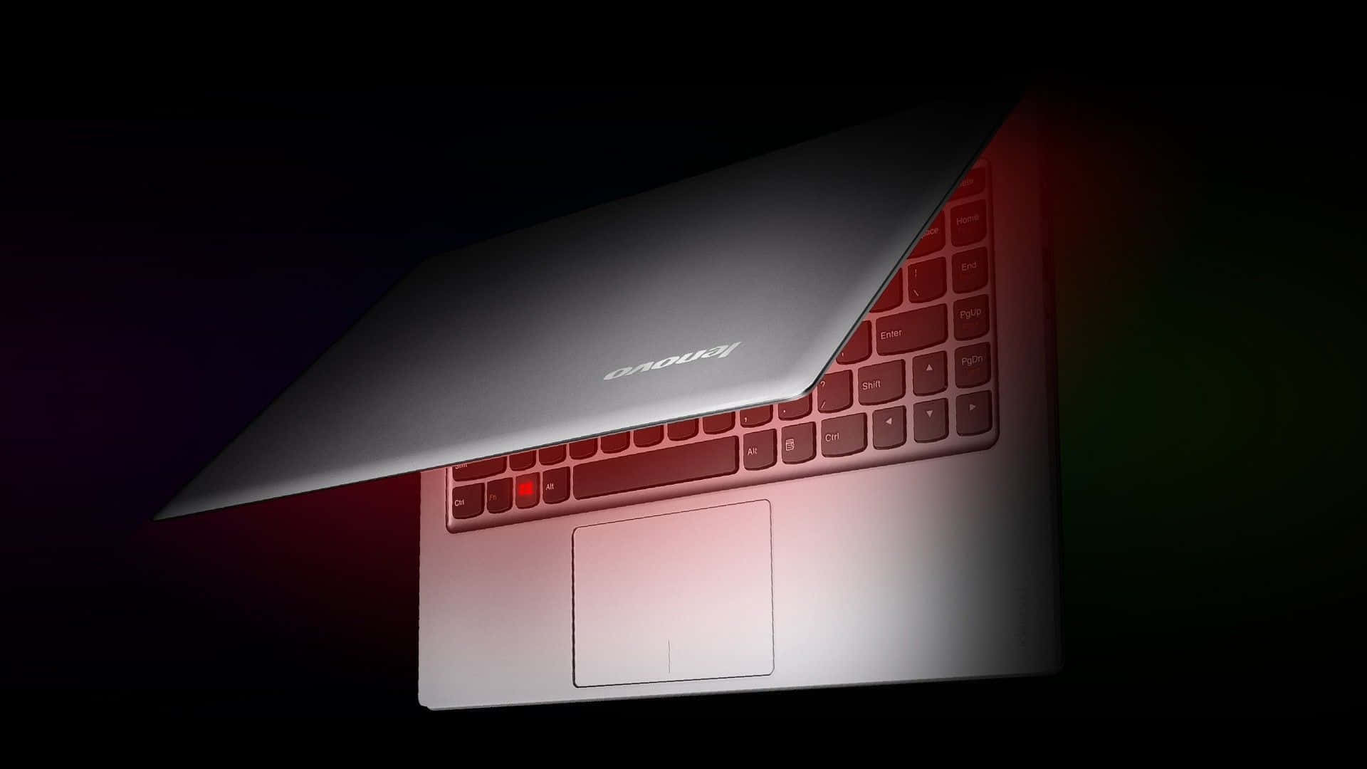 Lenovo 桌布 壁紙 — 一部時尚的銀色手提電腦在黑暗背景下傾斜打開，紅色環境照明突顯其鍵盤和觸控板。