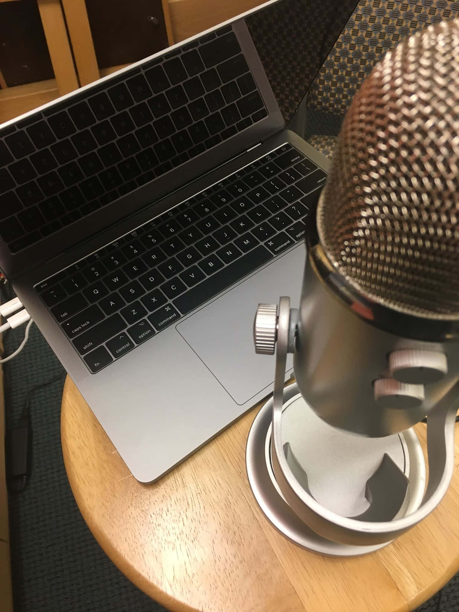 Podcasts 桌布 壁紙 — 一部時尚的銀色手提電腦旁邊放著一個專業錄音室麥克風，位於一個舒適的室內工作空間的木桌上。