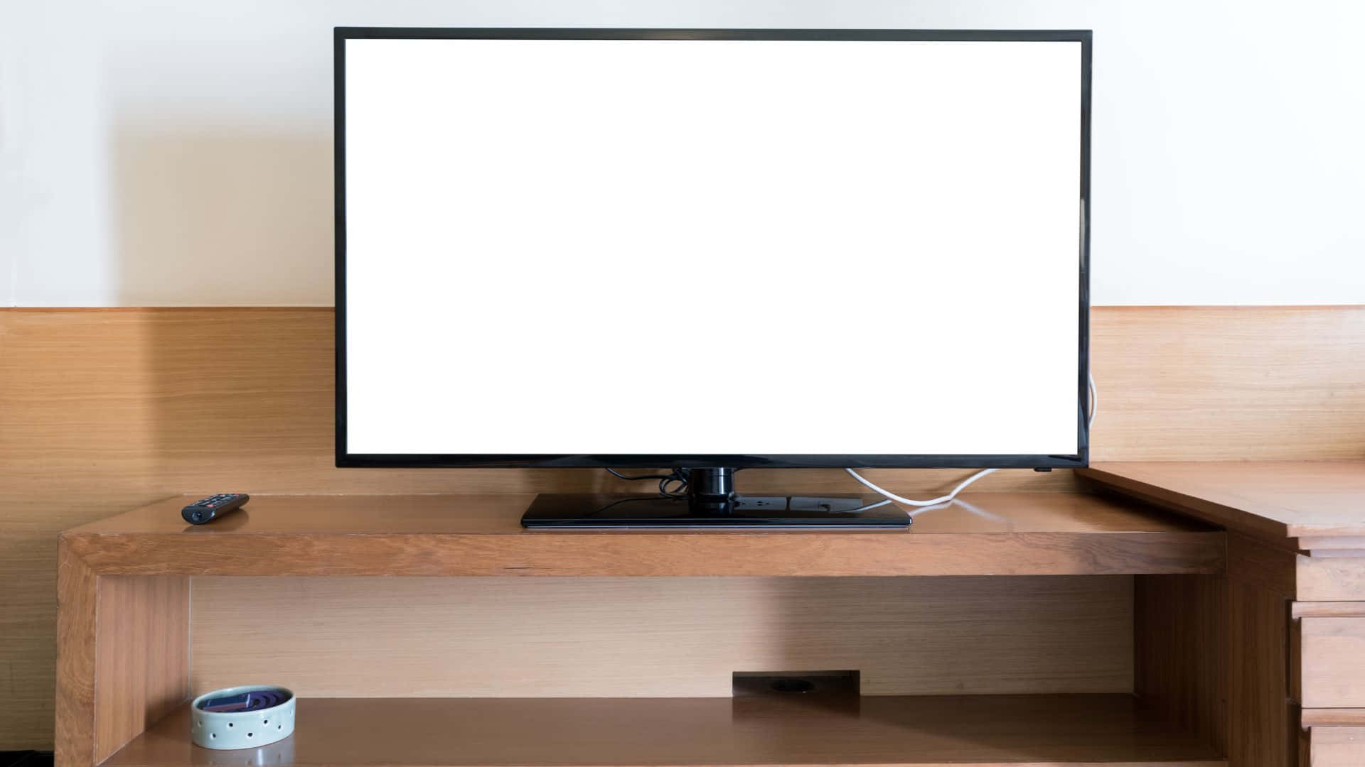 Computer Screen 桌布 壁紙 — 一部時尚的黑色電視機，帶有空白白色屏幕，居中放置在淺色木質媒體櫃上，下方有遙控器和時鐘。