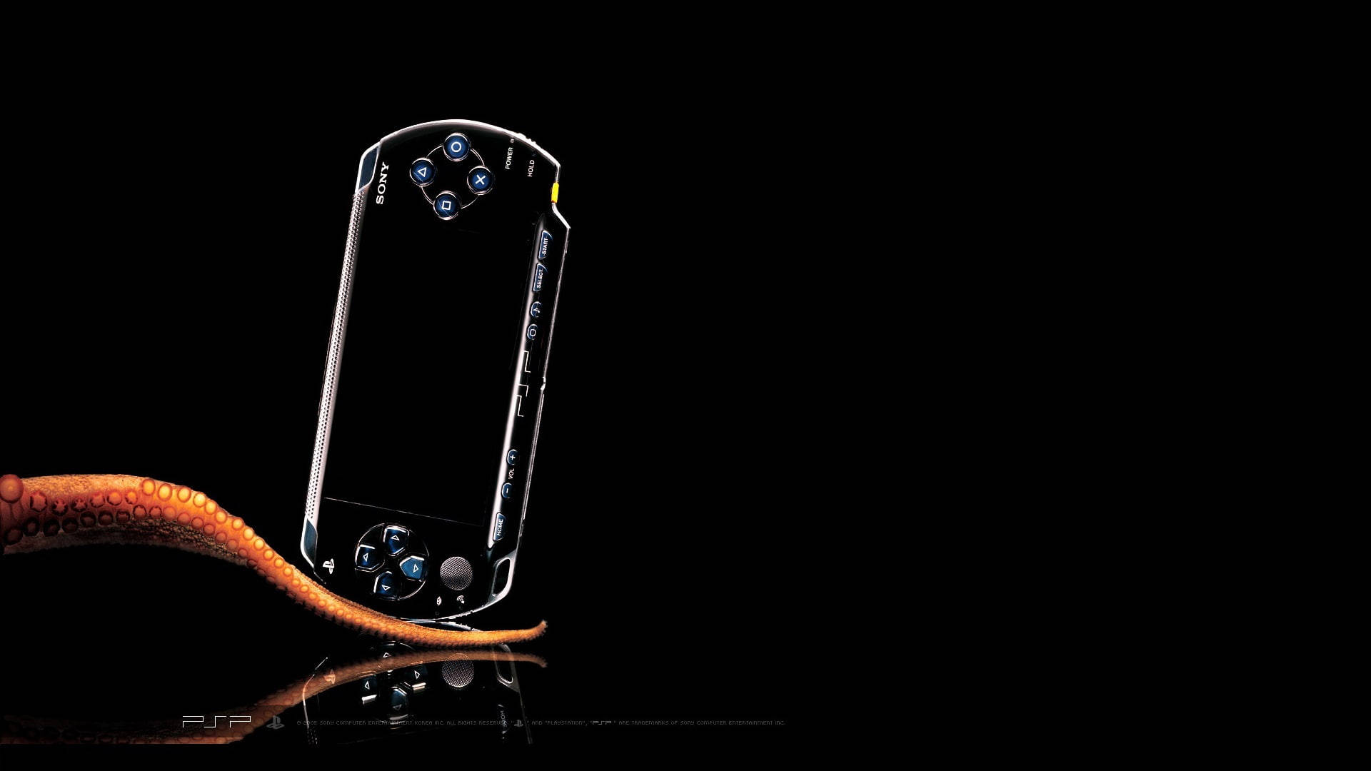 PlayStation 桌布 壁紙 — 一部流線型銀色 PSP 主機直立於反光黑色表面上，下方有一條橙色八爪魚觸手蜷曲。