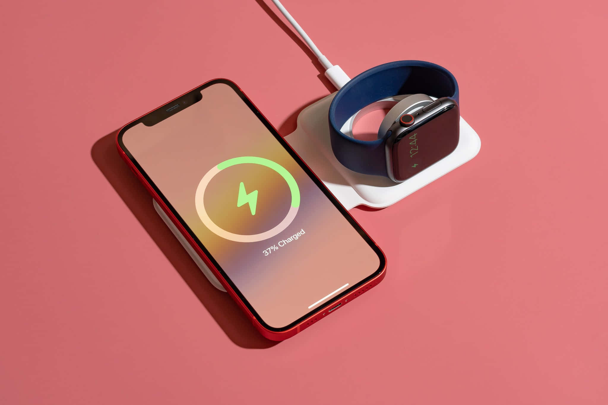 Wireless Charging 桌布 壁紙 — 一部紅色智能手機和智能手錶在純粉紅色背景下的白色充電座上充電。