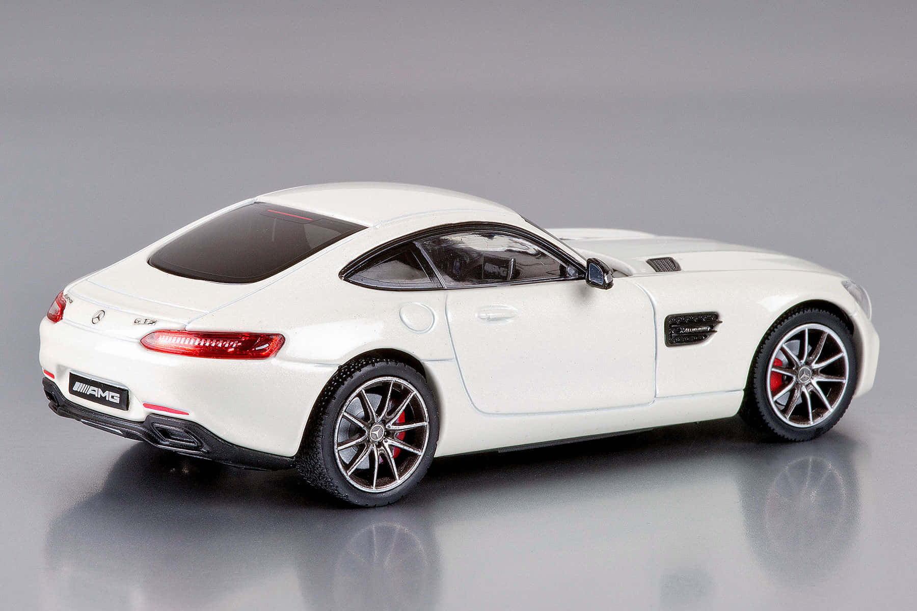 Car Model 桌布 壁紙 — 一部純白色AMG跑車模型，配備紅色制動卡鉗和時尚合金輪圈，在影樓燈光下拍攝於反光灰色表面。