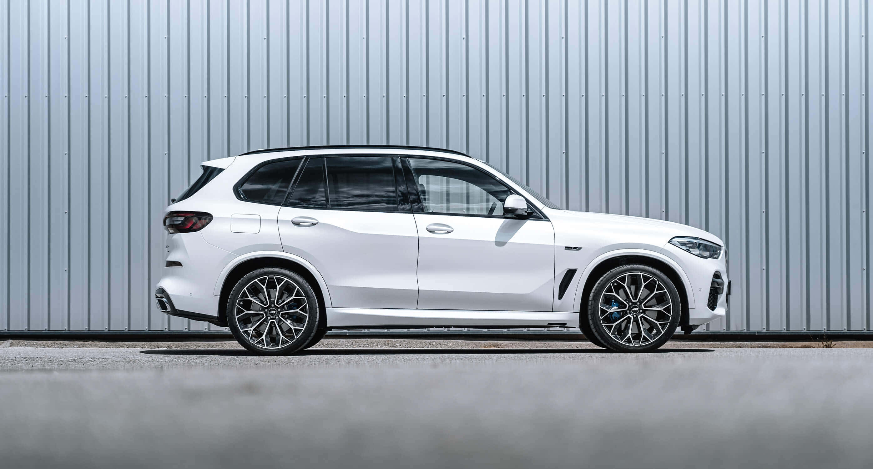 Bmw X5 桌布 壁紙 — 一部純白色BMW X5 SUV側身停靠在波紋金屬牆前，配以時尚合金輪圈和銳利現代線條。