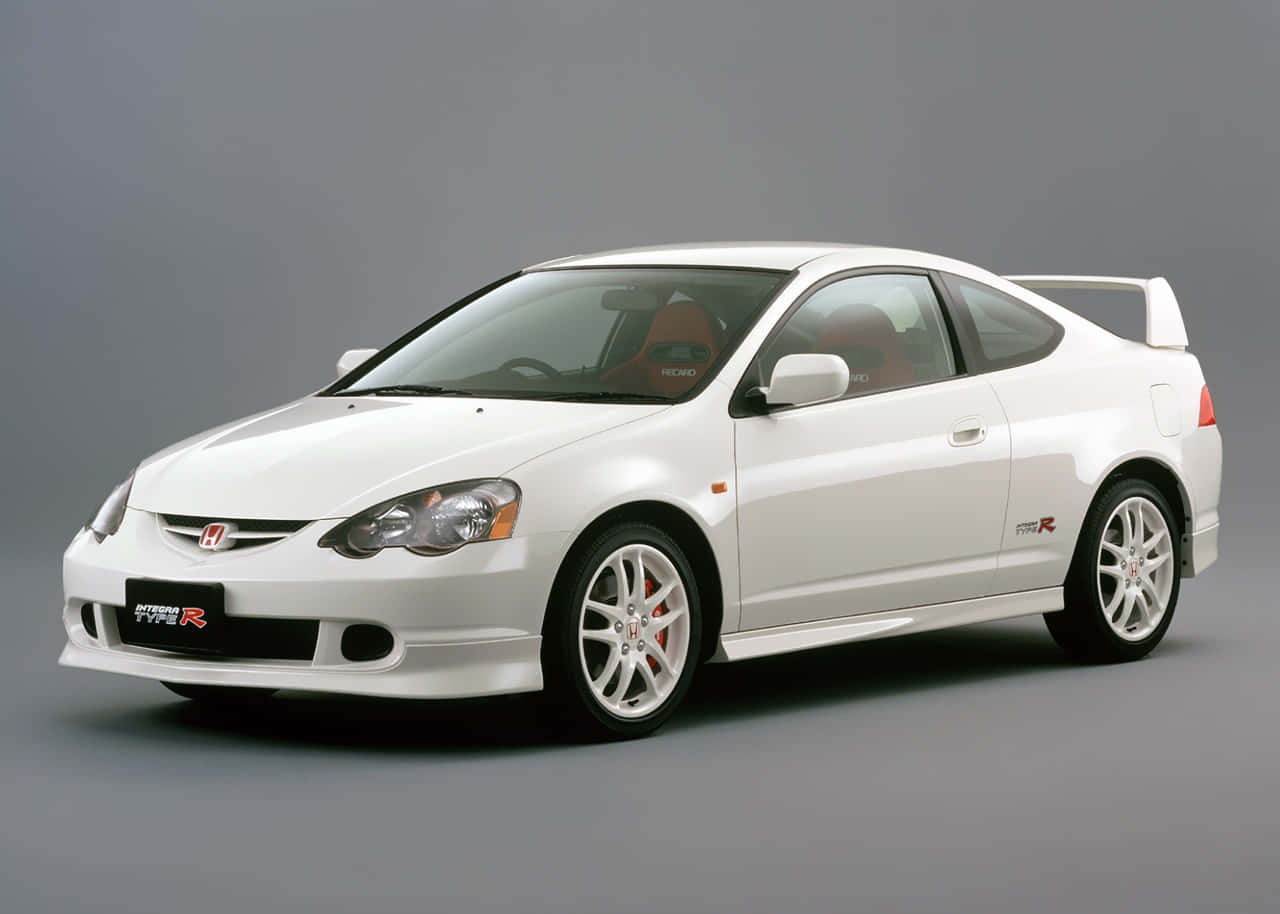 Honda Integra 桌布 壁紙 — 一部純白色的本田Integra Type R運動轎跑車，配備紅色內飾和後擾流板，置於中性灰色工作室背景前。