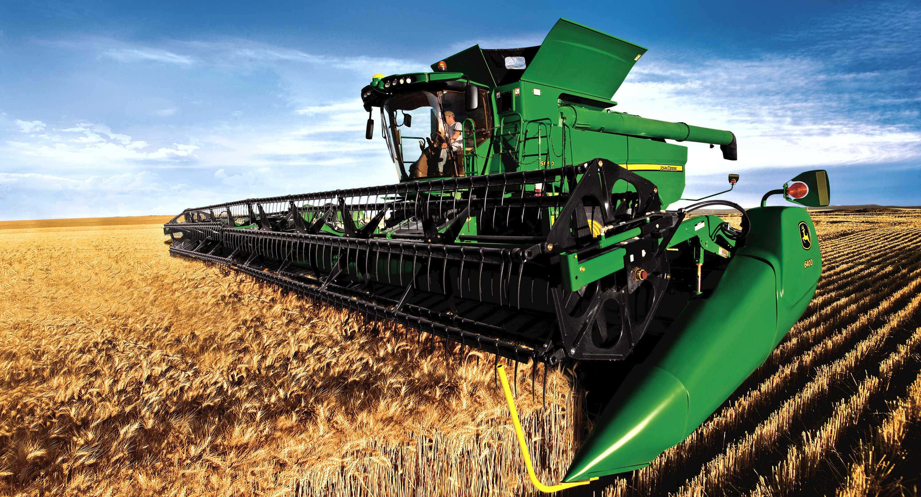 John Deere 桌布 壁紙 — 一部綠色的約翰迪爾聯合收割機在明亮的藍天白雲下收割金色的麥子。