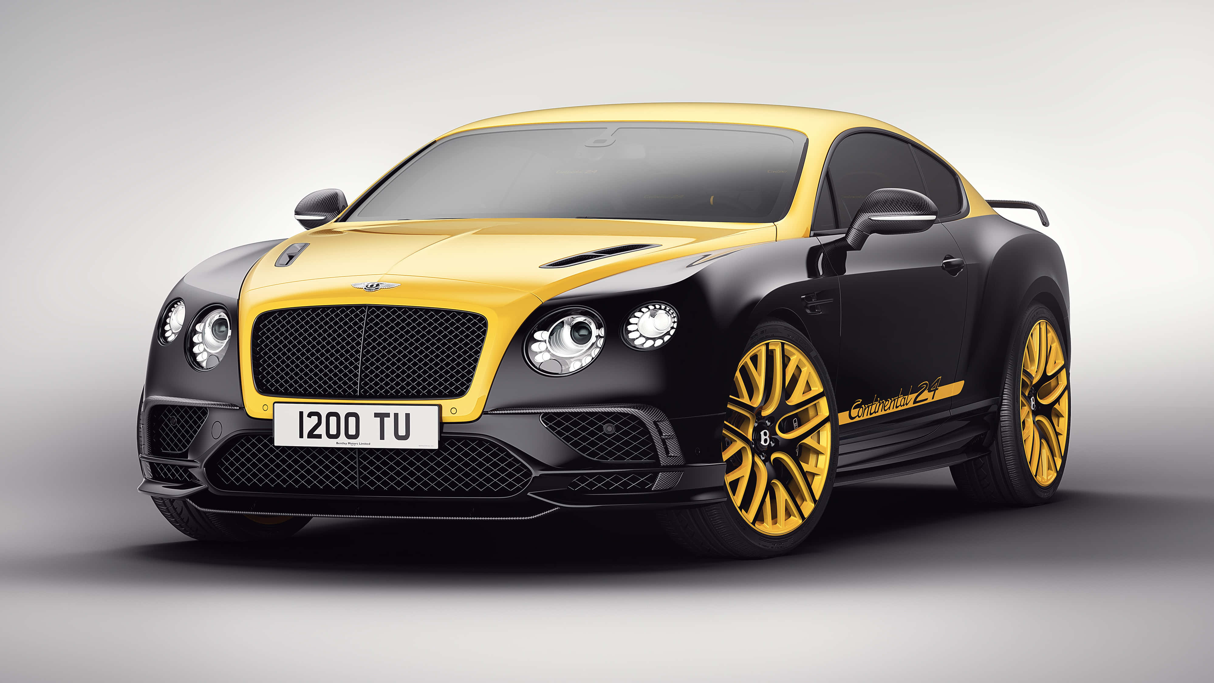 Bentley Continental Supersports 桌布 壁紙 — 一部線條流暢的賓利 Continental GT Speed，採用大膽的黃黑配色和金色輪圈，在簡約的攝影棚背景下展示。