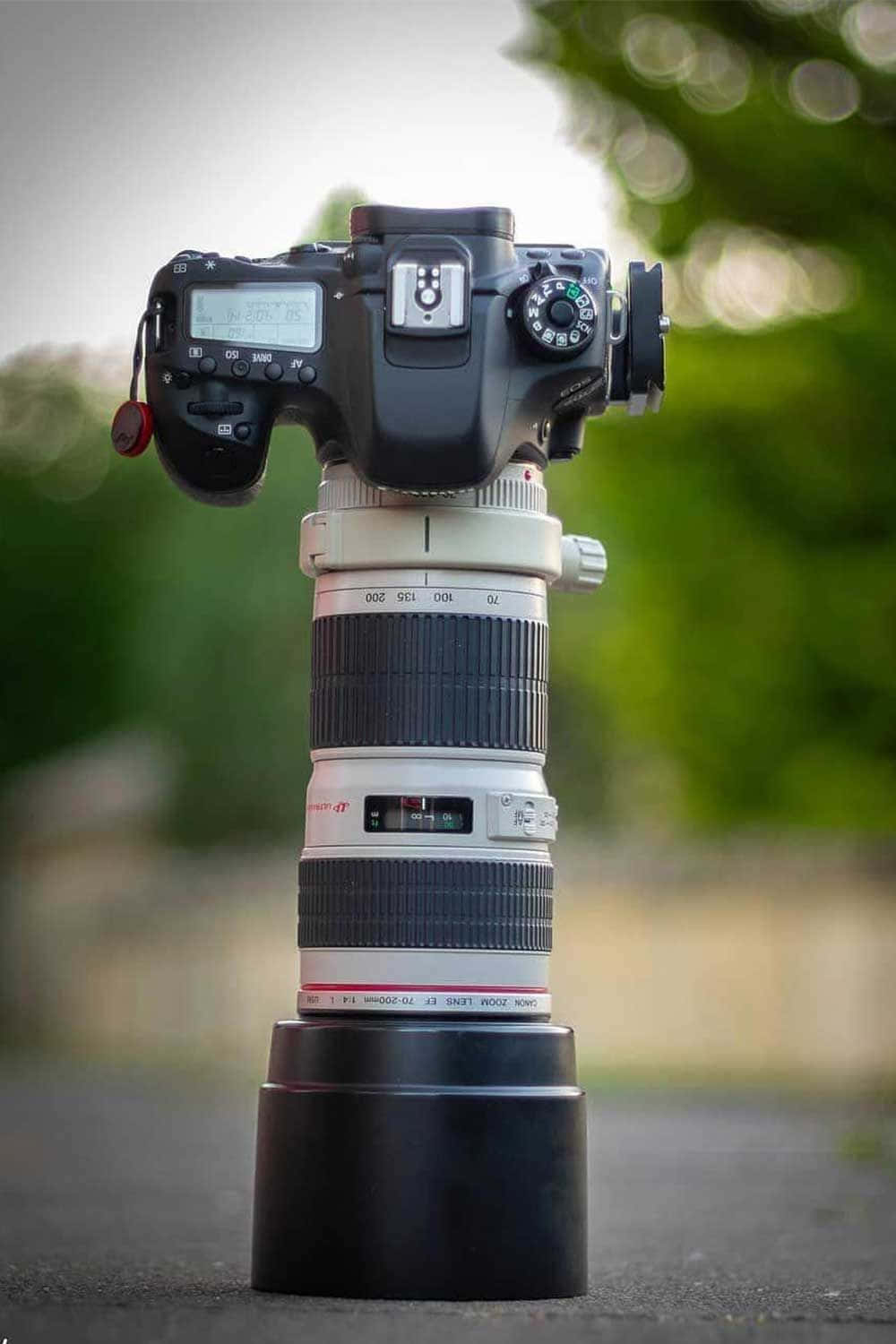 Dslr Camera 桌布 壁紙 — 一部配備長焦距鏡頭的DSLR相機直立於鋪砌表面上，背景為模糊的綠色。