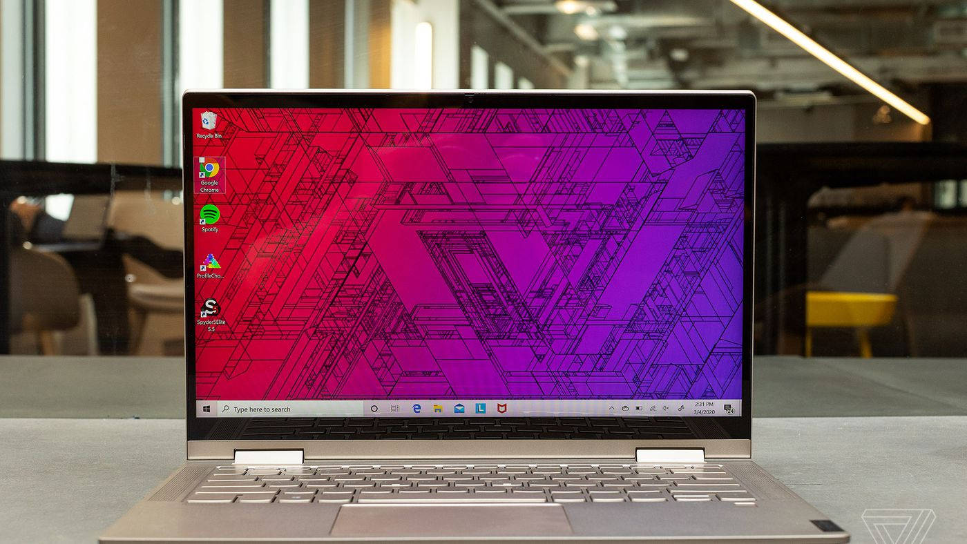 Laptop 桌布 壁紙 — 一部銀色手提電腦在現代書桌上顯示鮮豔的紅到紫漸變壁紙，帶有幾何線條藝術。