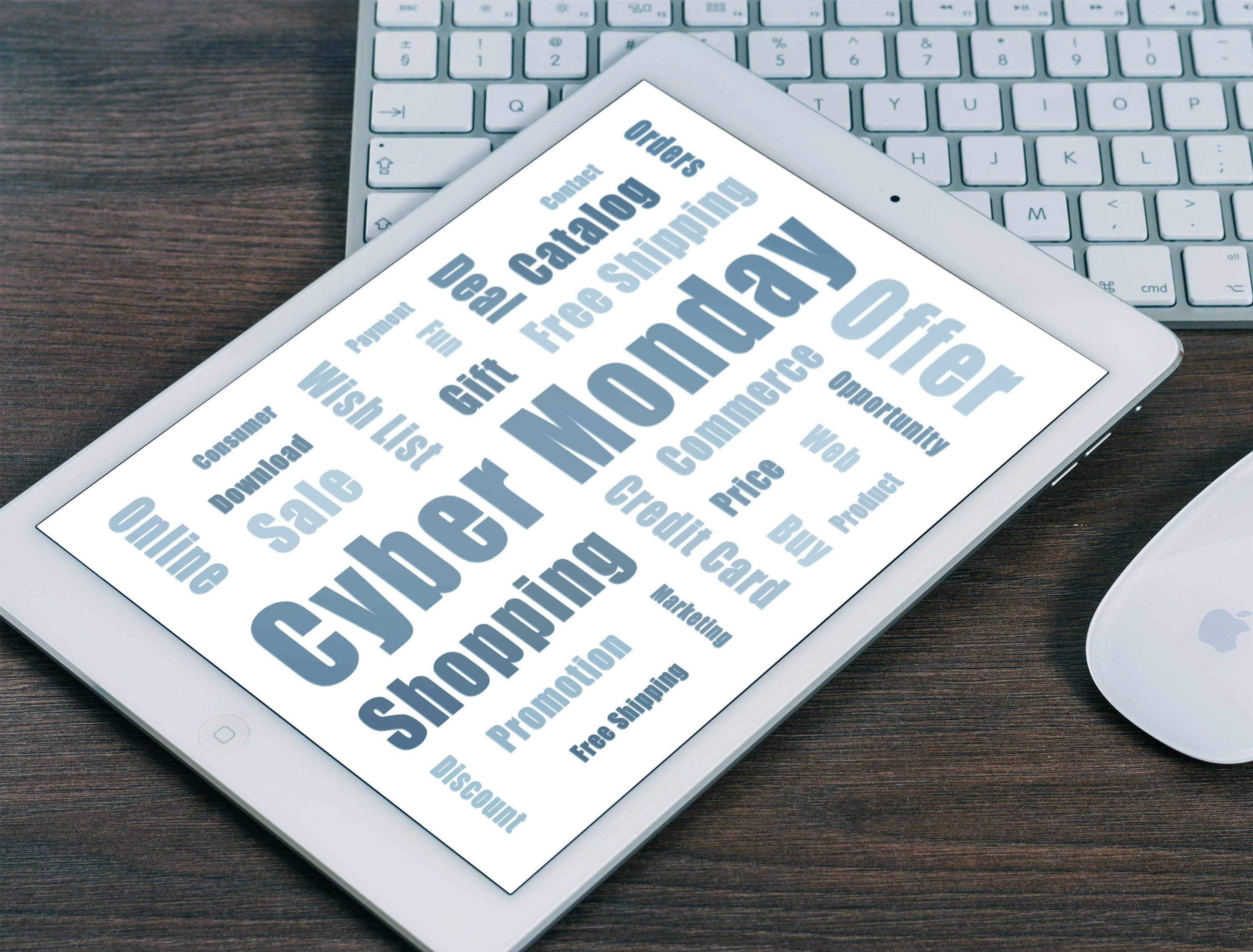 科技 桌布 壁紙 — 一部顯示「Cyber Monday」銷售字詞的平板電腦放在木桌上，旁邊有鍵盤和滑鼠。