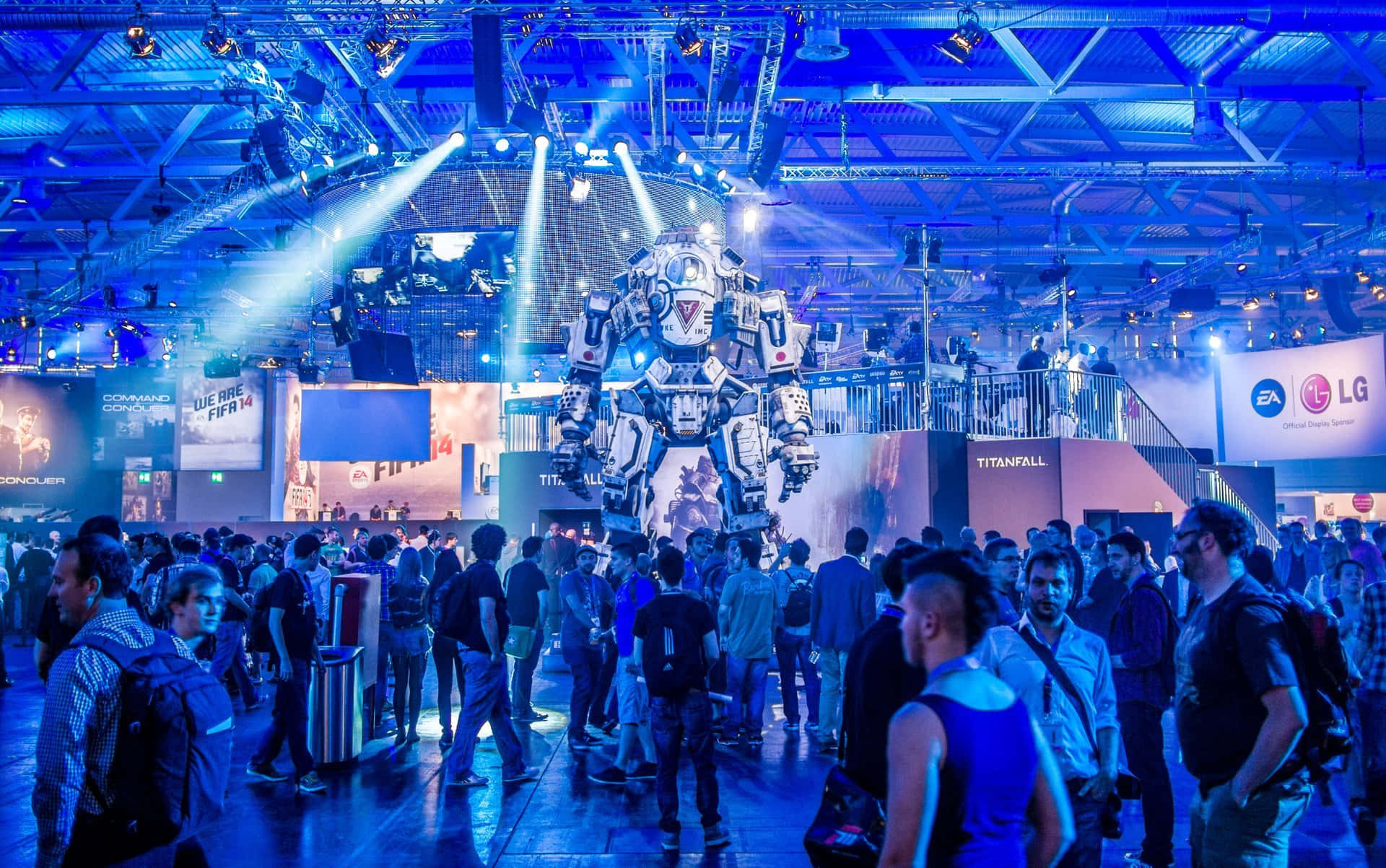 Gaming Conventions 桌布 壁紙 — 一部高聳的 Titanfall 機甲在擁擠的遊戲展覽場地上被藍色聚光燈照亮。