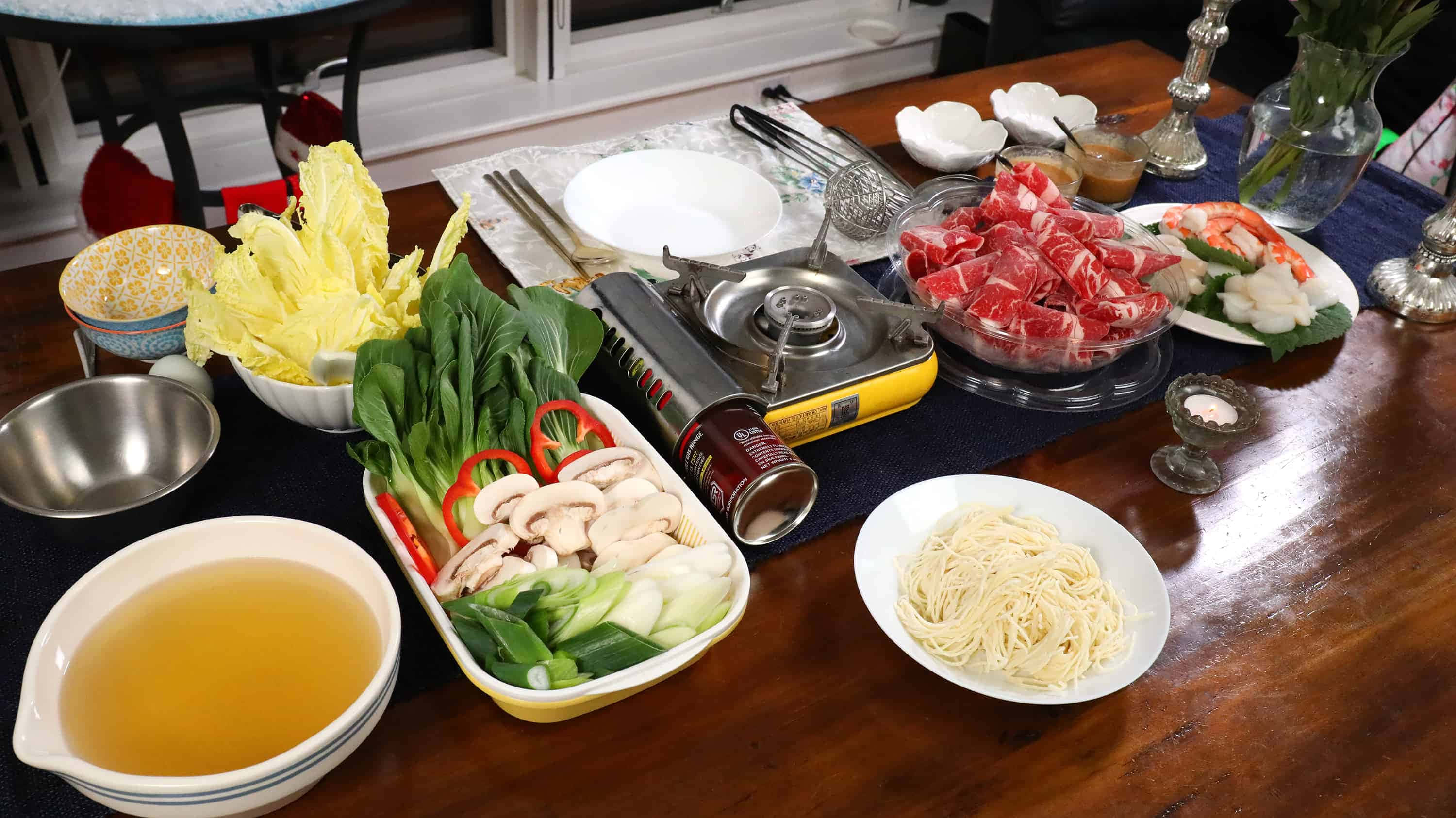一鍋齊全的日式涮涮鍋 壁紙 — 一張木桌上擺滿了火鍋食材，包括生肉、蝦、蔬菜和湯底，準備烹煮。