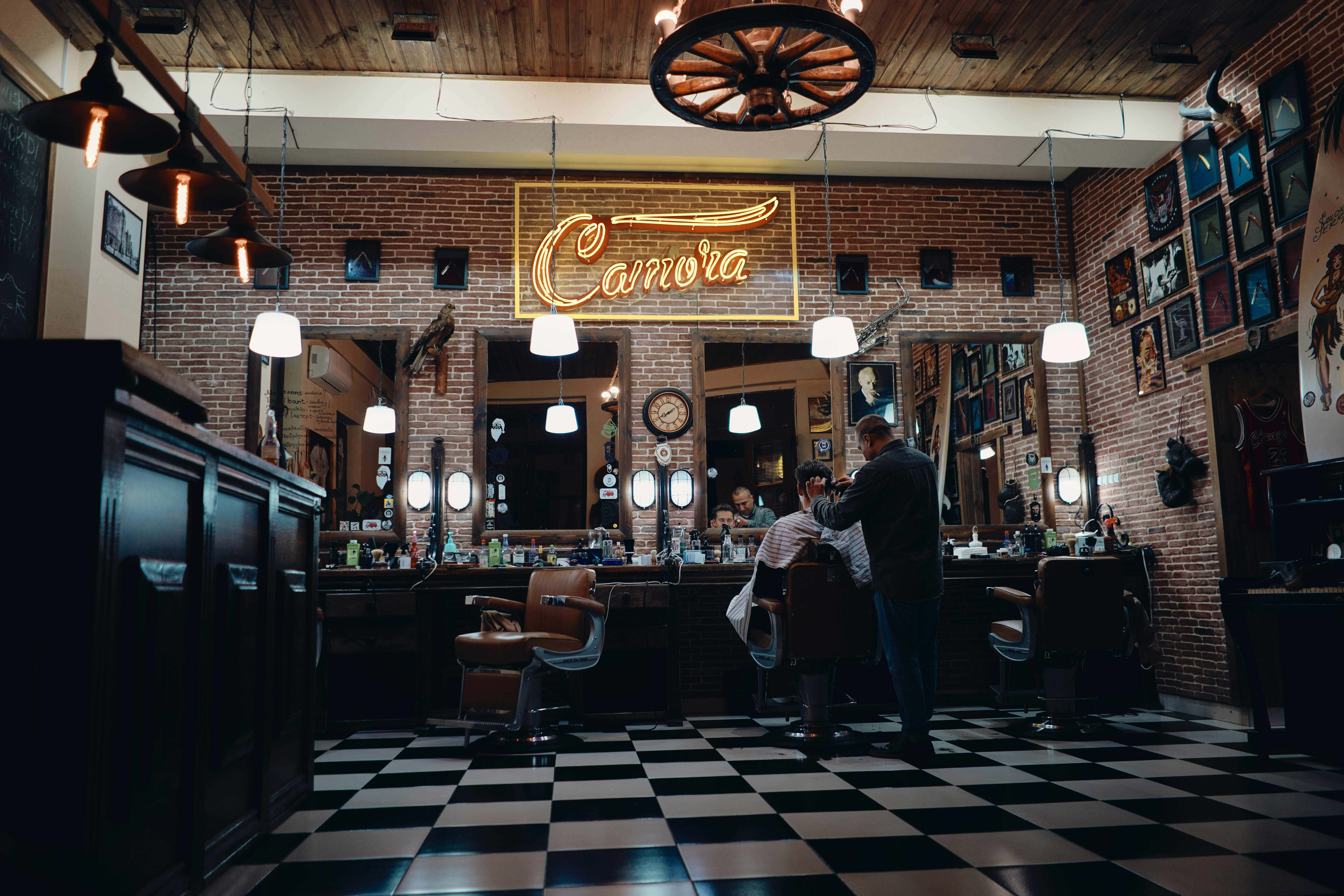 Barber 桌布 壁紙 — 一間復古理髮店，磚牆、棋盤地板和發光的霓虹燈招牌照亮了正在剪髮的理髮師。