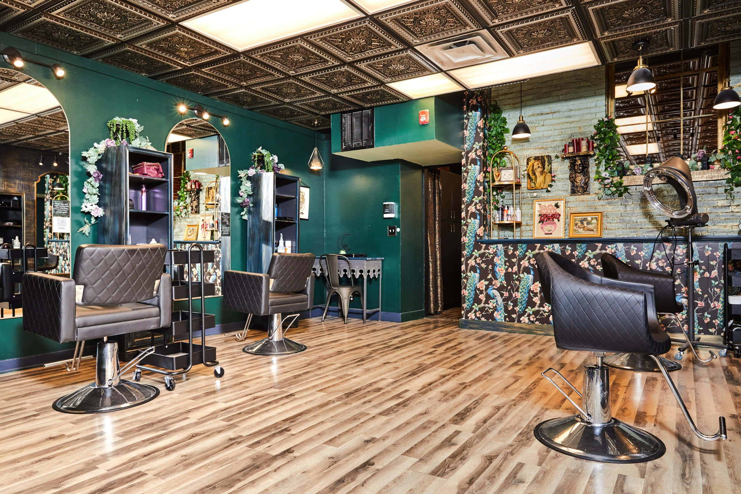 Hair Salon 桌布 壁紙 — 一間時尚復古風格的理髮店，擁有翡翠綠牆壁、木地板和黑色皮革椅，上方是華麗的天花板瓷磚。