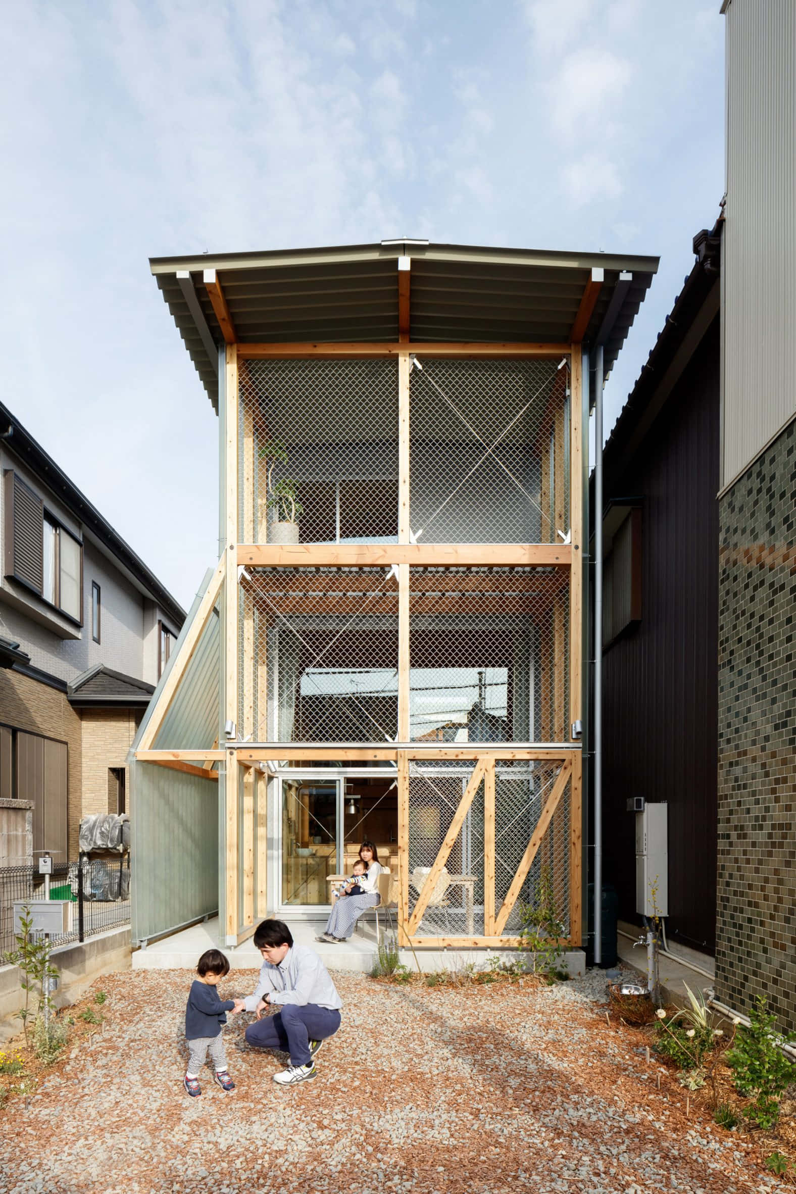 Minimalist Architecture 桌布 壁紙 — 一間現代木屋，配有紗窗和碎石庭院，一名男子與小孩跪著，而一名女子坐在屋內。