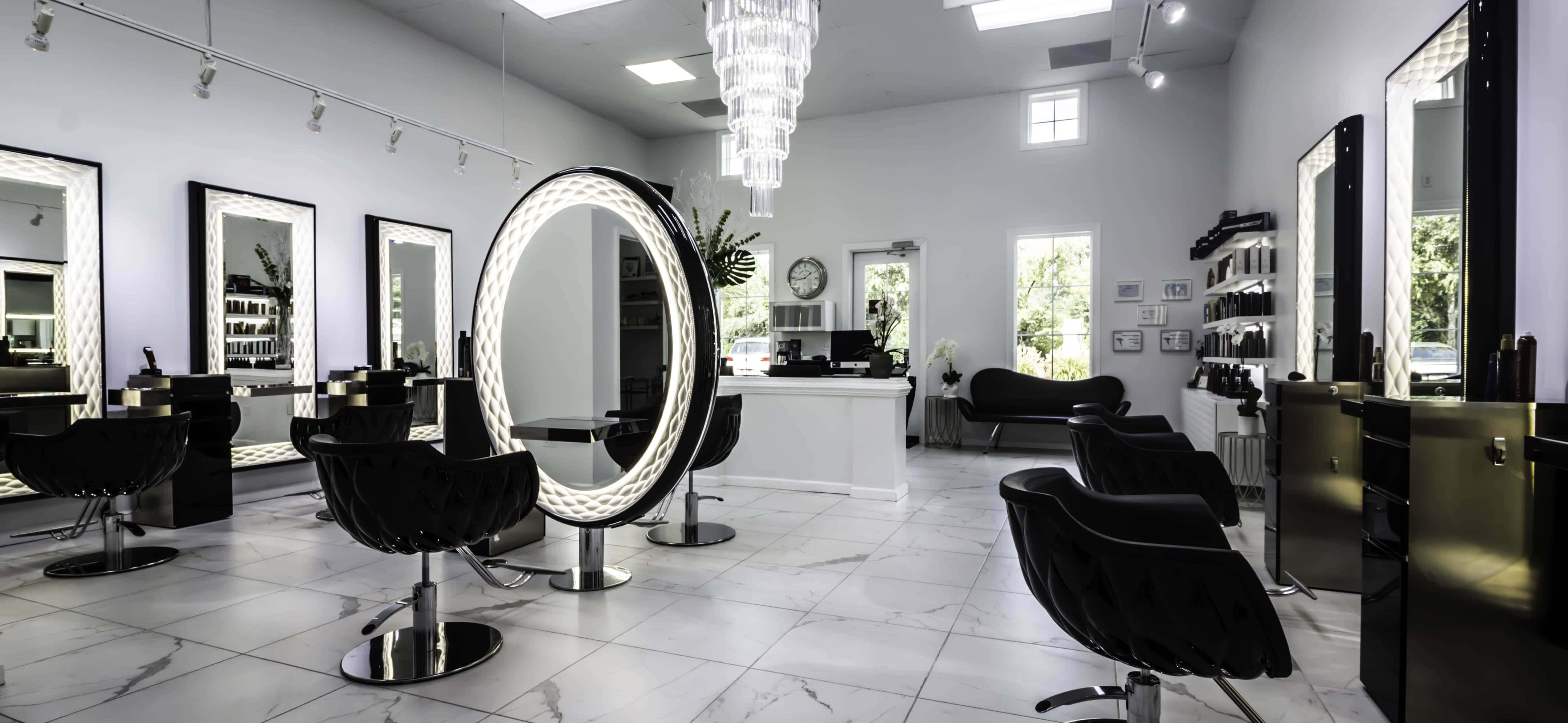 Hair Salon 桌布 壁紙 — 一間現代豪華髮廊，配有黑色椅子、白色大理石地板和在水晶吊燈下發光的圓形鏡子。