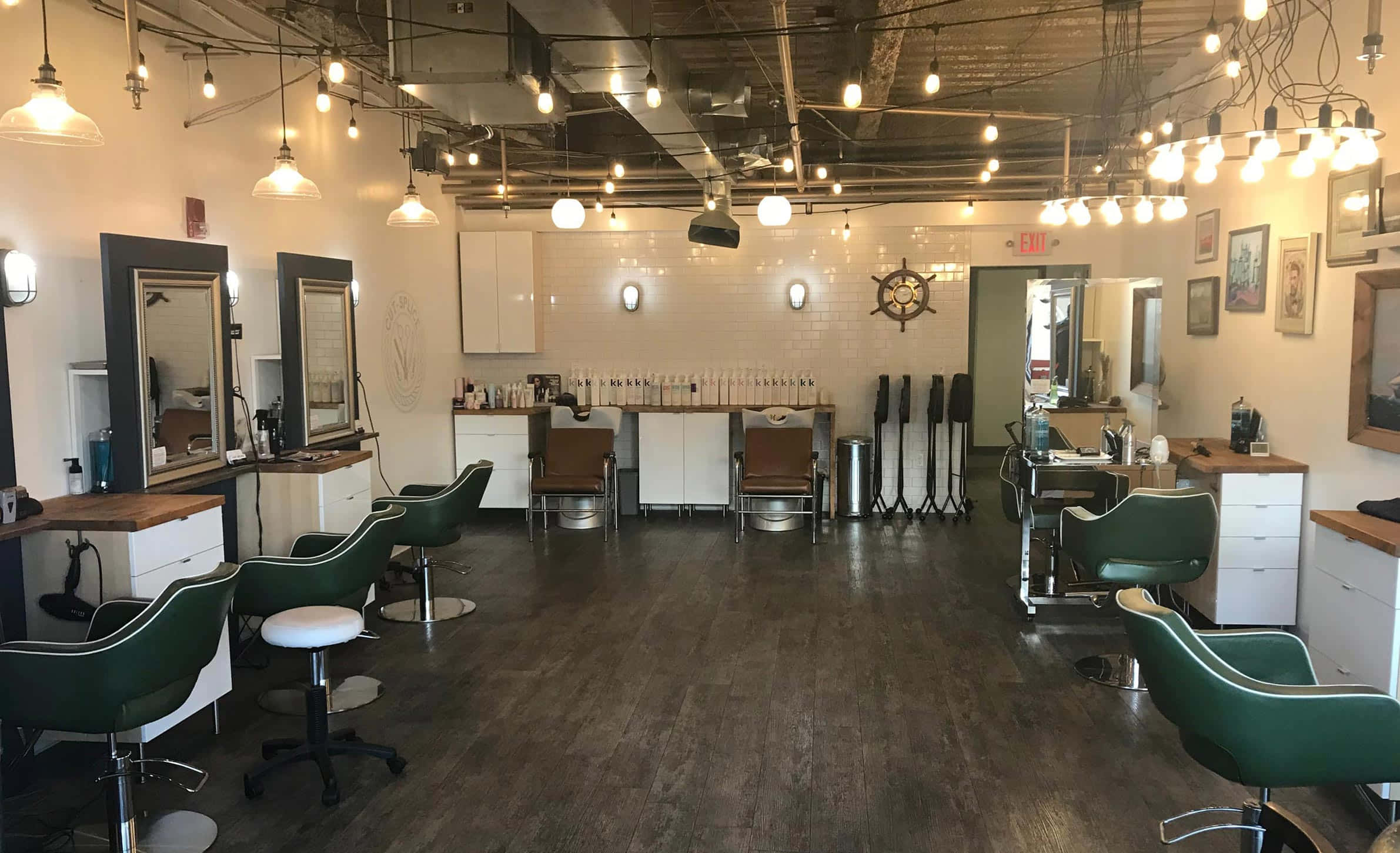 Hair Salon 桌布 壁紙 — 一間現代髮廊，配有綠色椅子、白色櫥櫃和裸露的天花板燈，營造出時尚的工業風格。