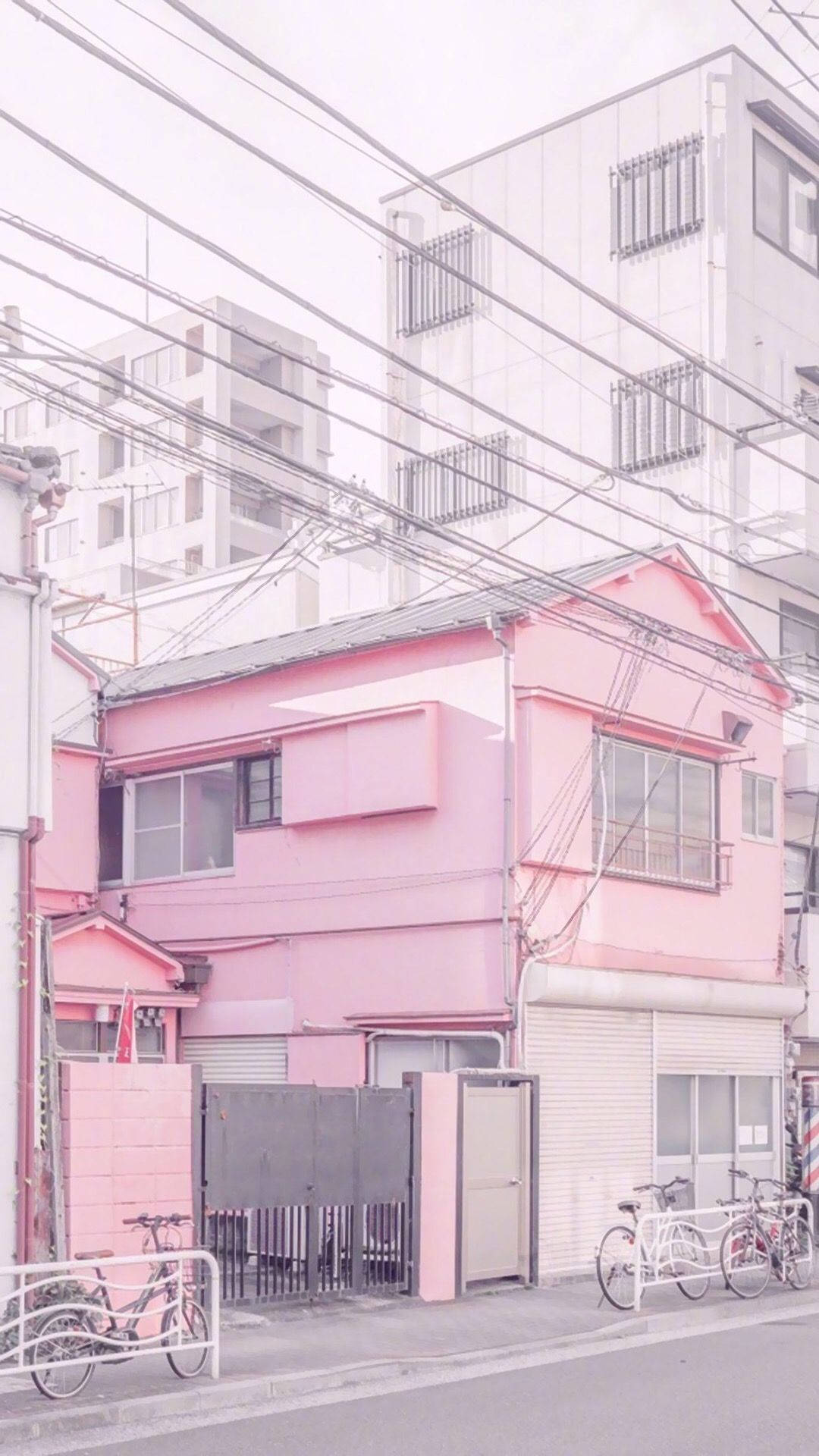 Home 桌布 壁紙 — 一間粉紅色房子，外面停著單車，矗立在寧靜的城市小巷中，天空柔和多雲。